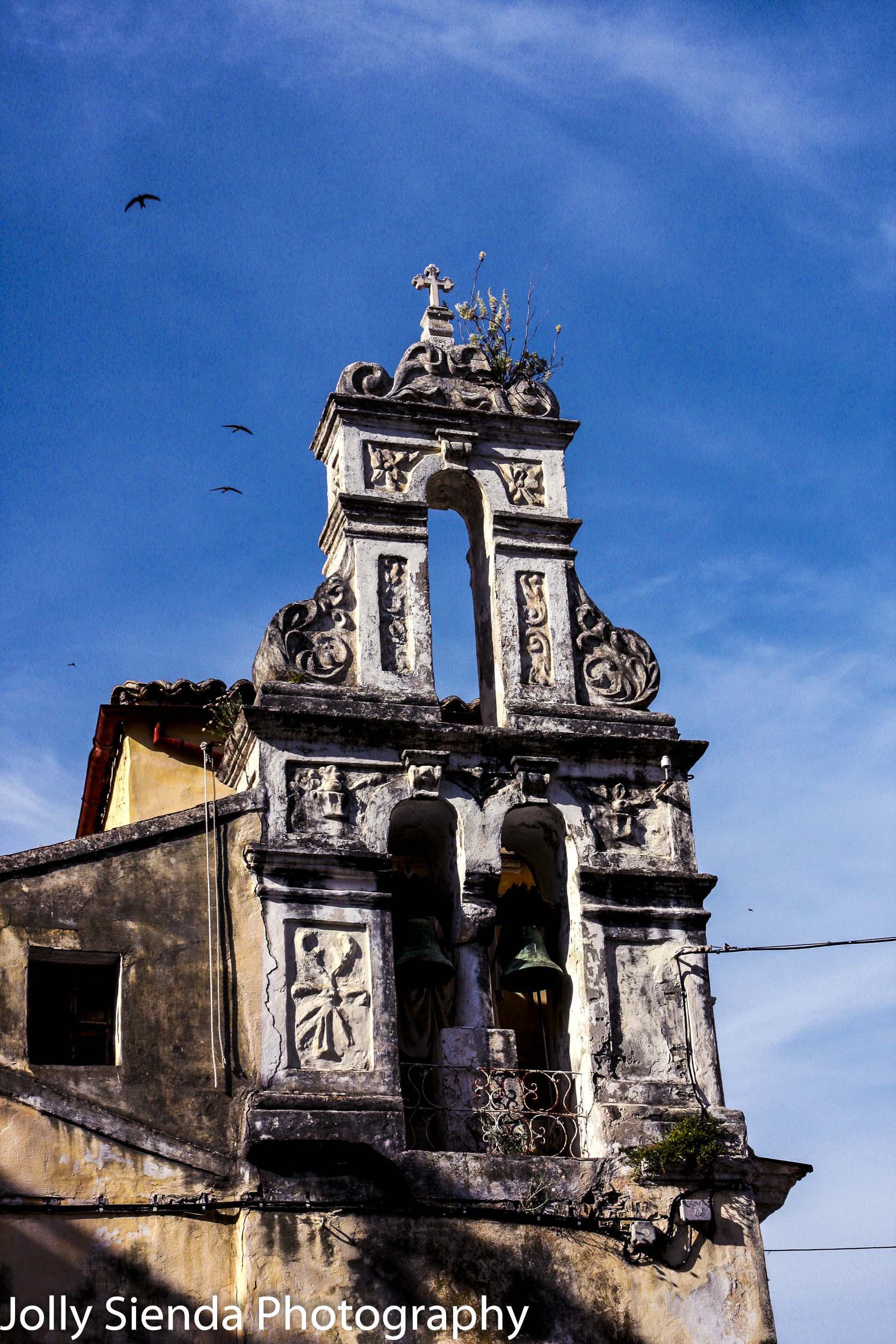 Old, ornate church facade with bronze bells and seagulls 