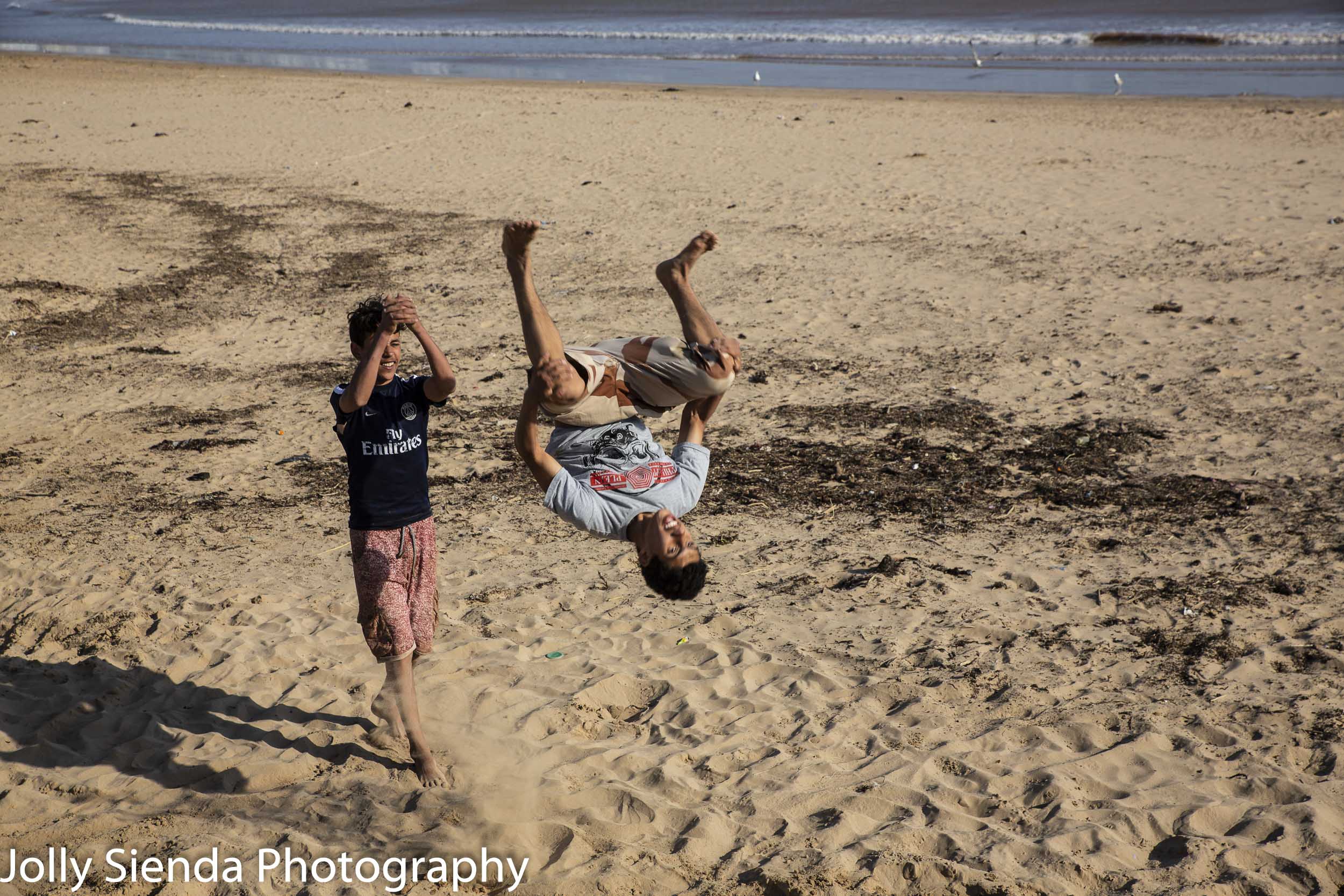 Men doing somersaults on the beach