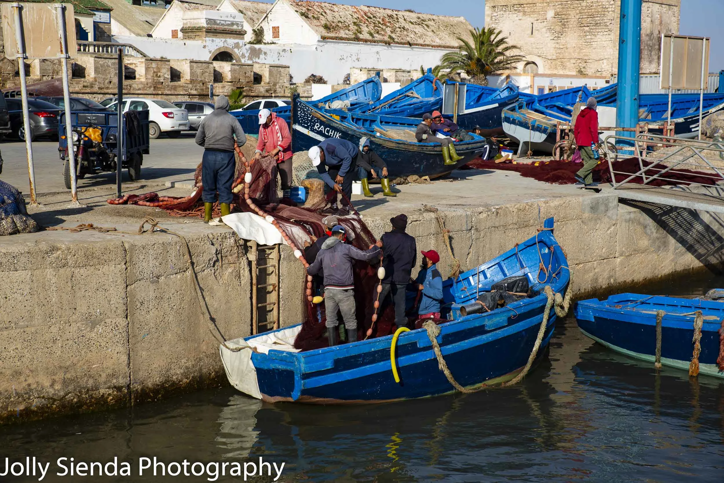 Fishermen hoist nets into the wooden boats