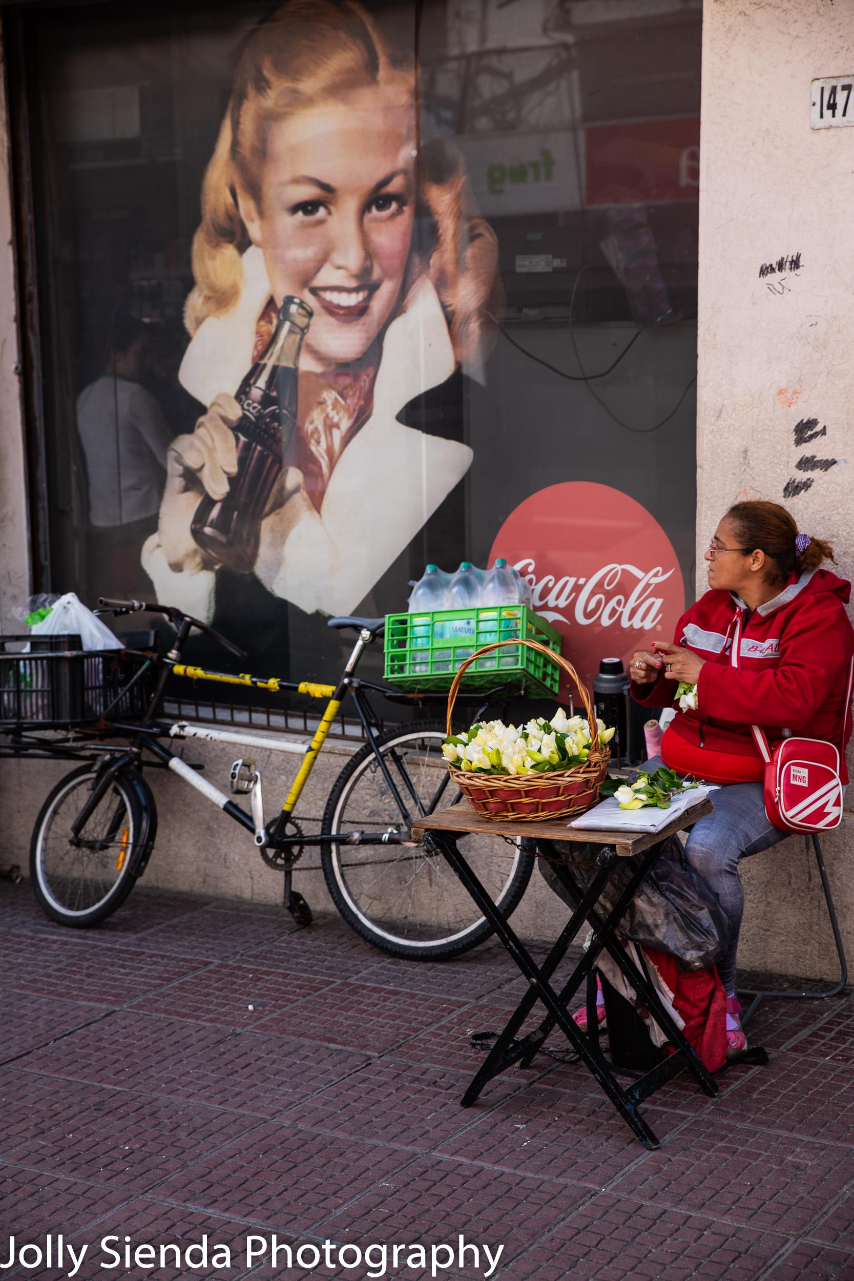 Woman selling vegetables and a Coca Cola sign