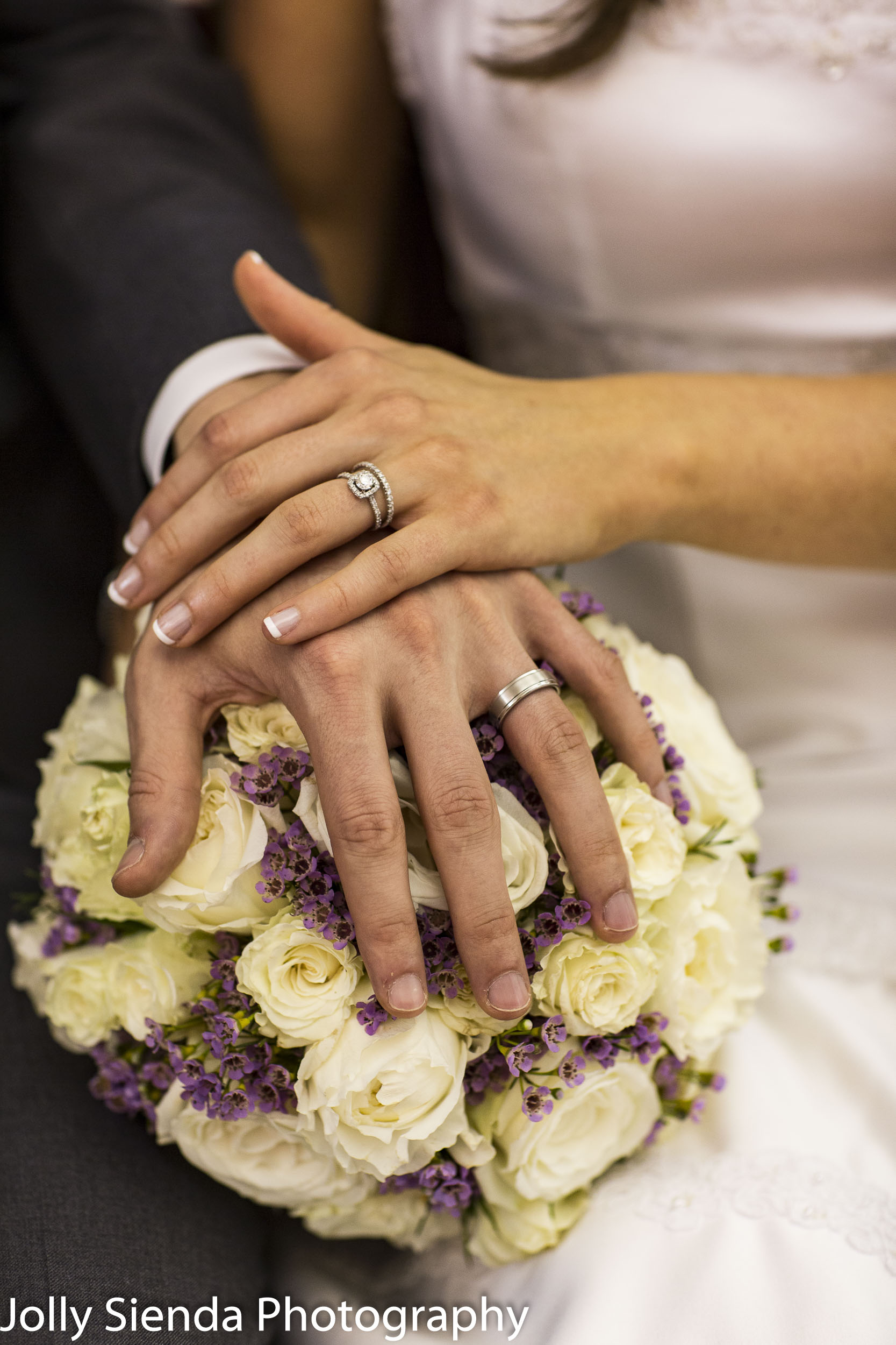 Hands clasped with his and her diamond wedding rings over weddin