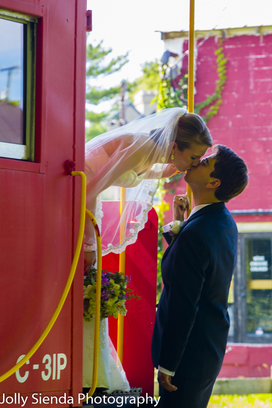 Bride kisses the groom from a red caboose train