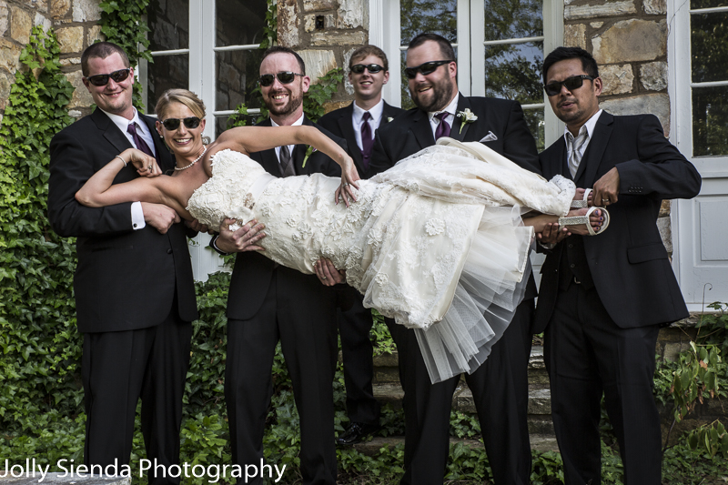 Portrait of cool, fun wedding with the wedding party holding the