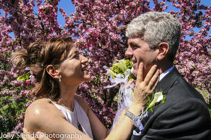 Bride and groom are about to kiss in front of blooming cherry bl