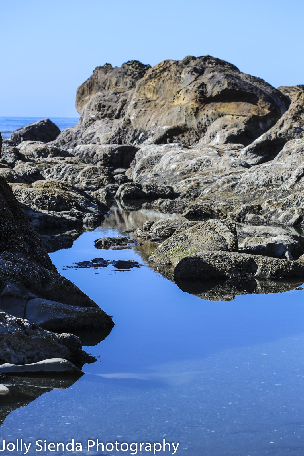 Clear blue tide pool and coastal boulders