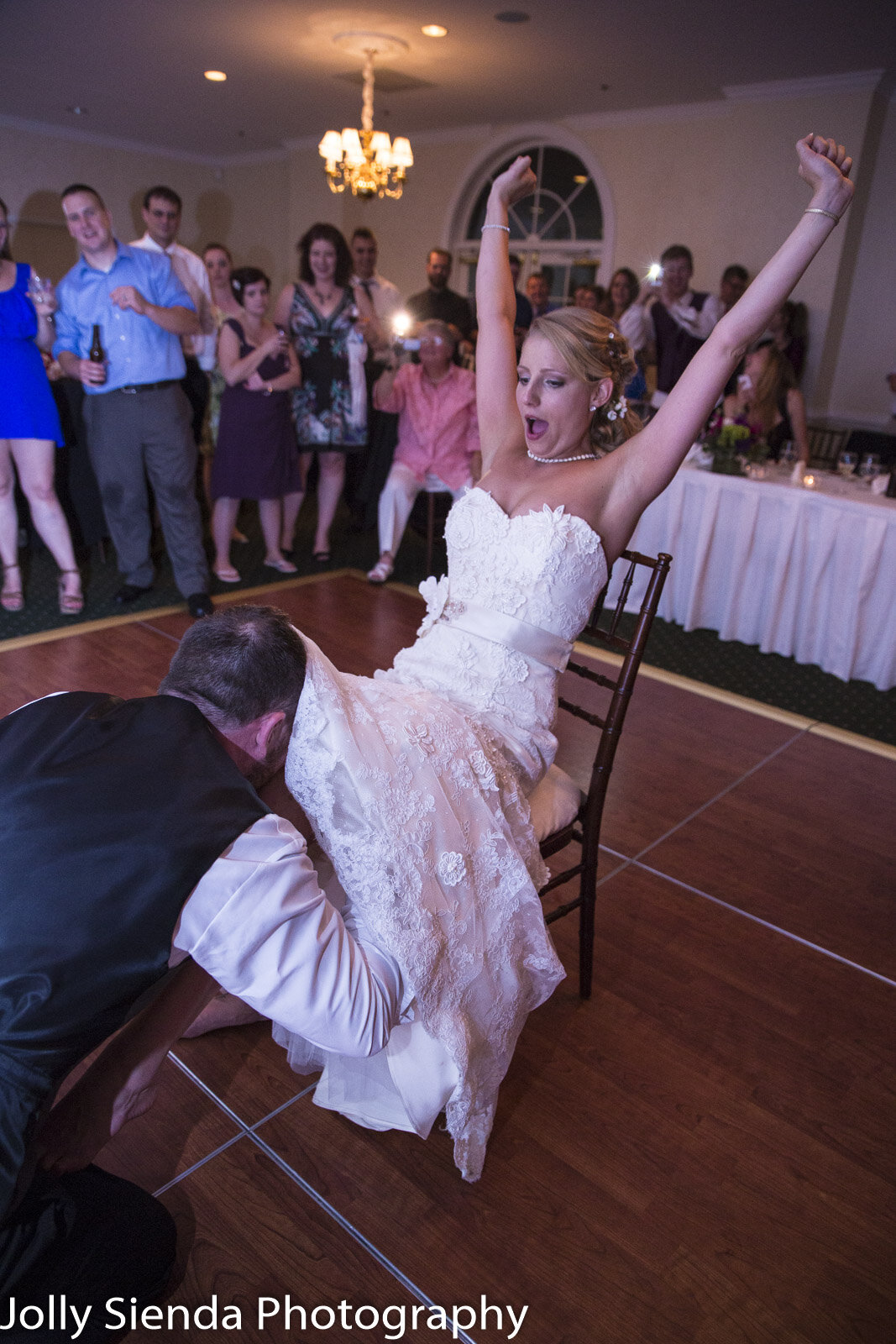 Portrait of a groom getting the brides garter belt from the brid