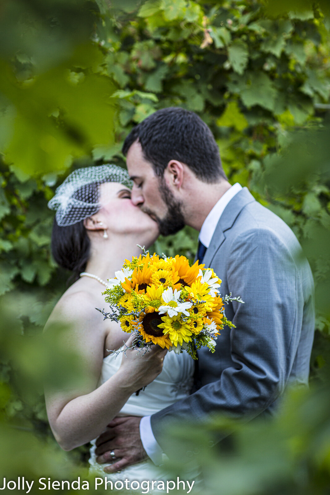 Vineyard wedding, bride and groom kiss in the sunflower vineyard