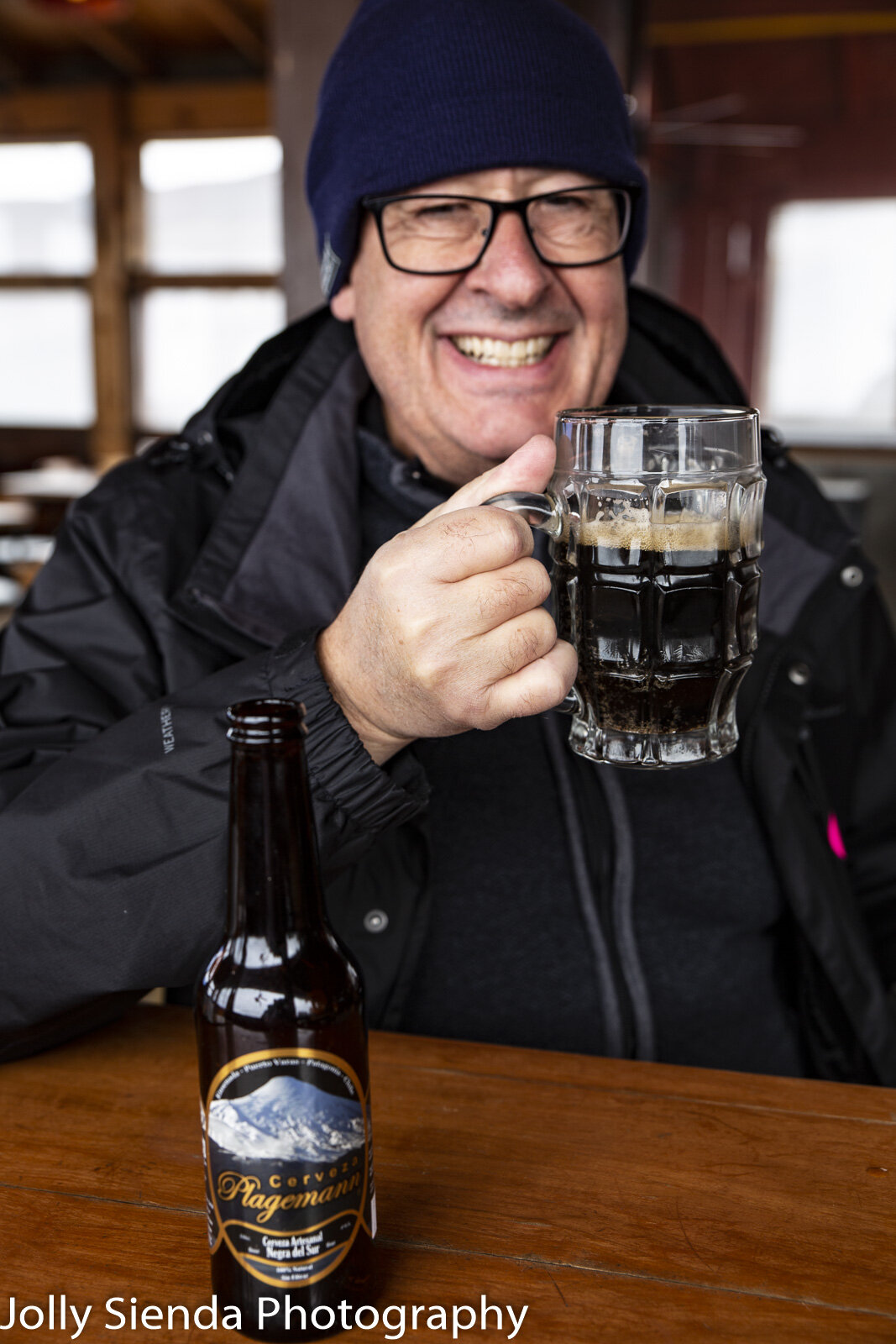 Man wearing a ski cap enjoys a beer 