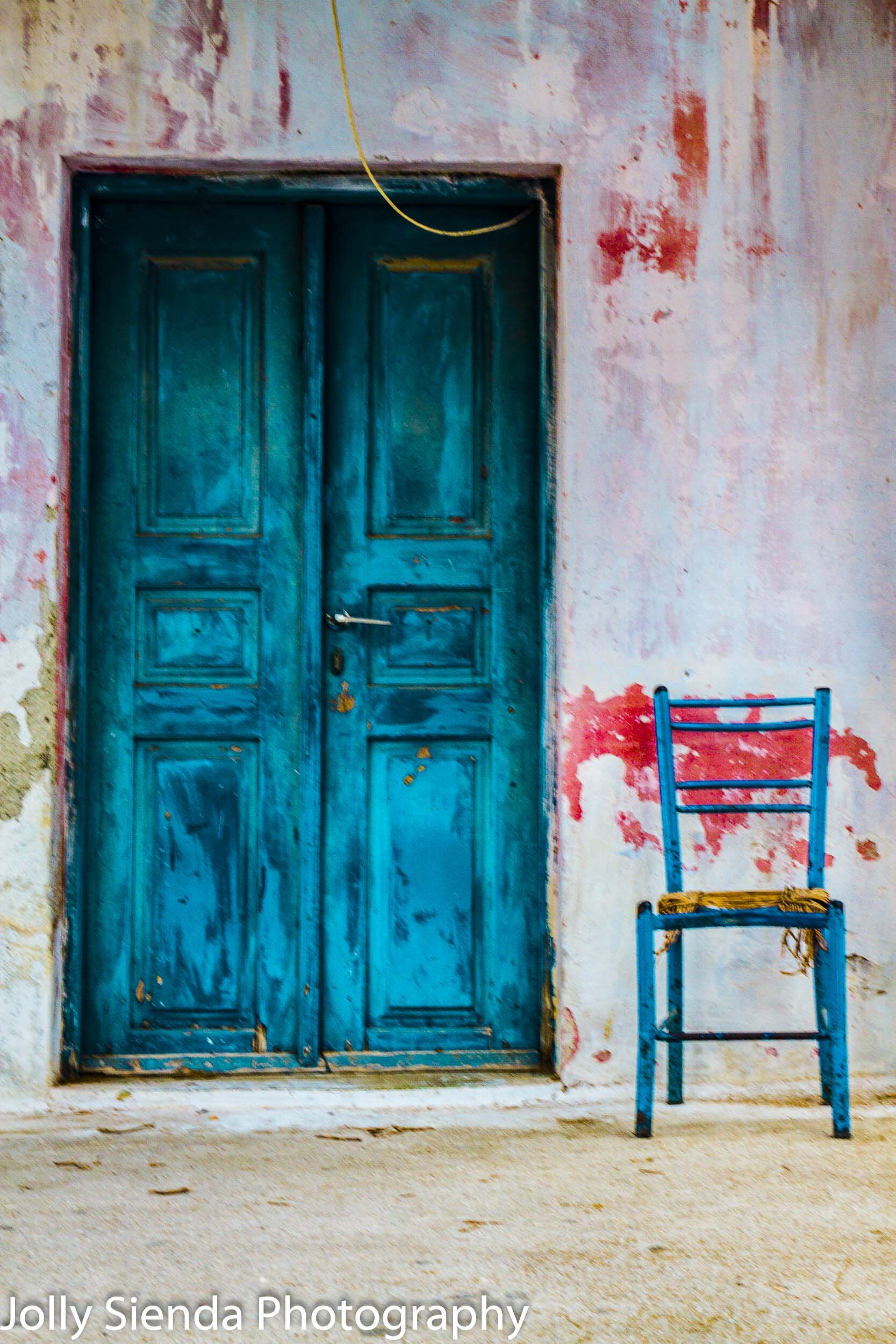Detressed blue door chair against a stucco wall