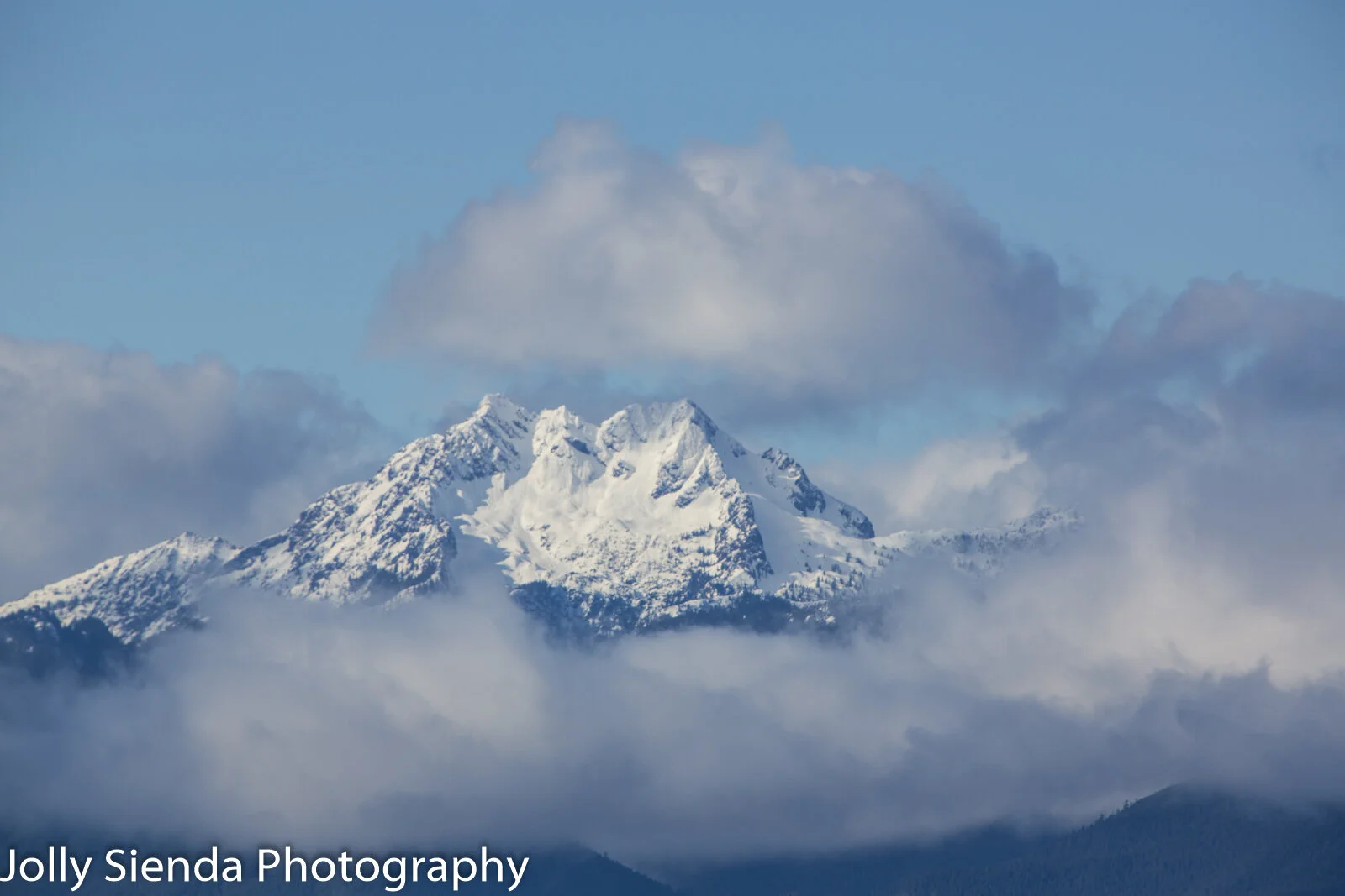 Fresh snow and pastel clouds surround rhe Brothers Mountain