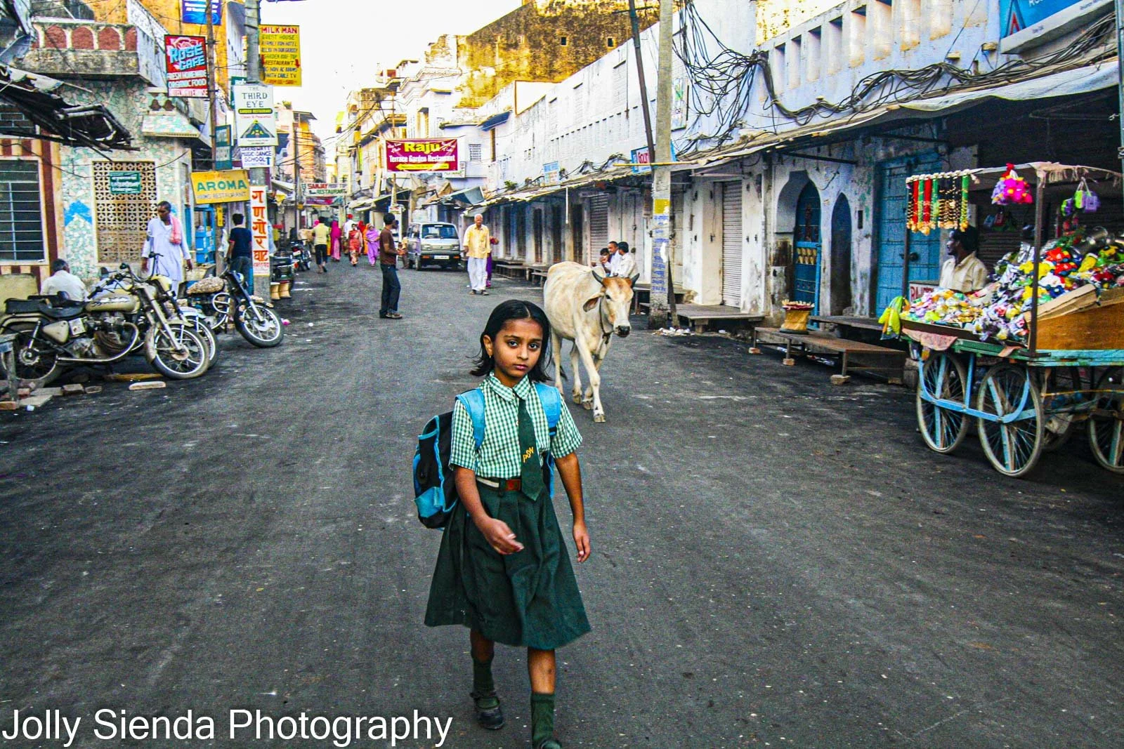 School girl in uniform walks down market street with a horned co