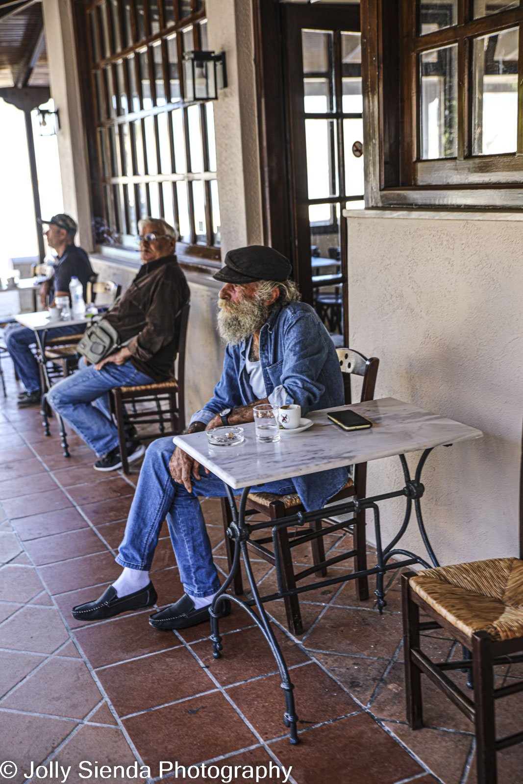 Bearded man with cap drinks at a cafe with coffee