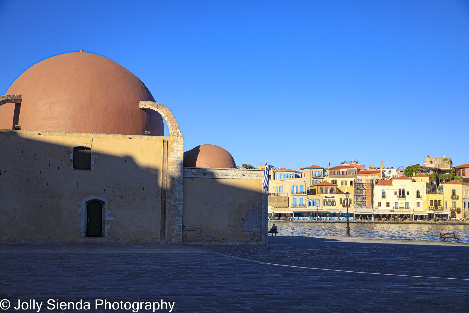 Greek church red dome, sun kissed harbor village and the bay