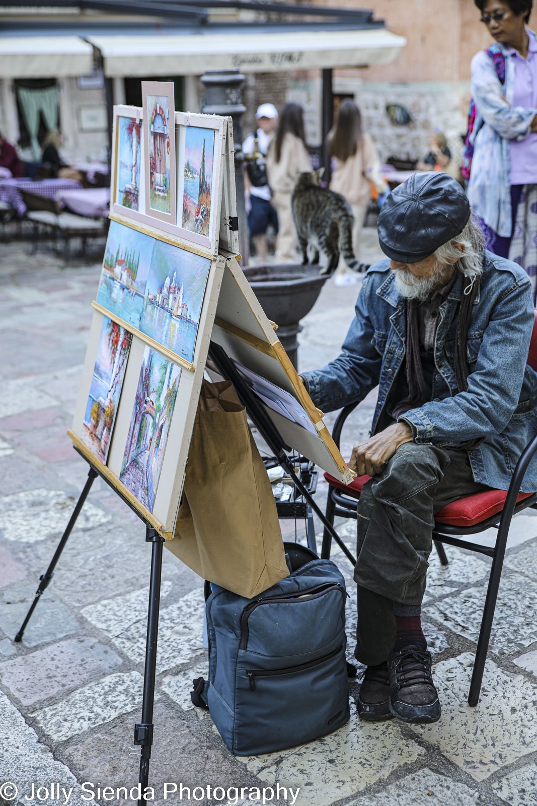 Painter paints on easel in Kotor old town square