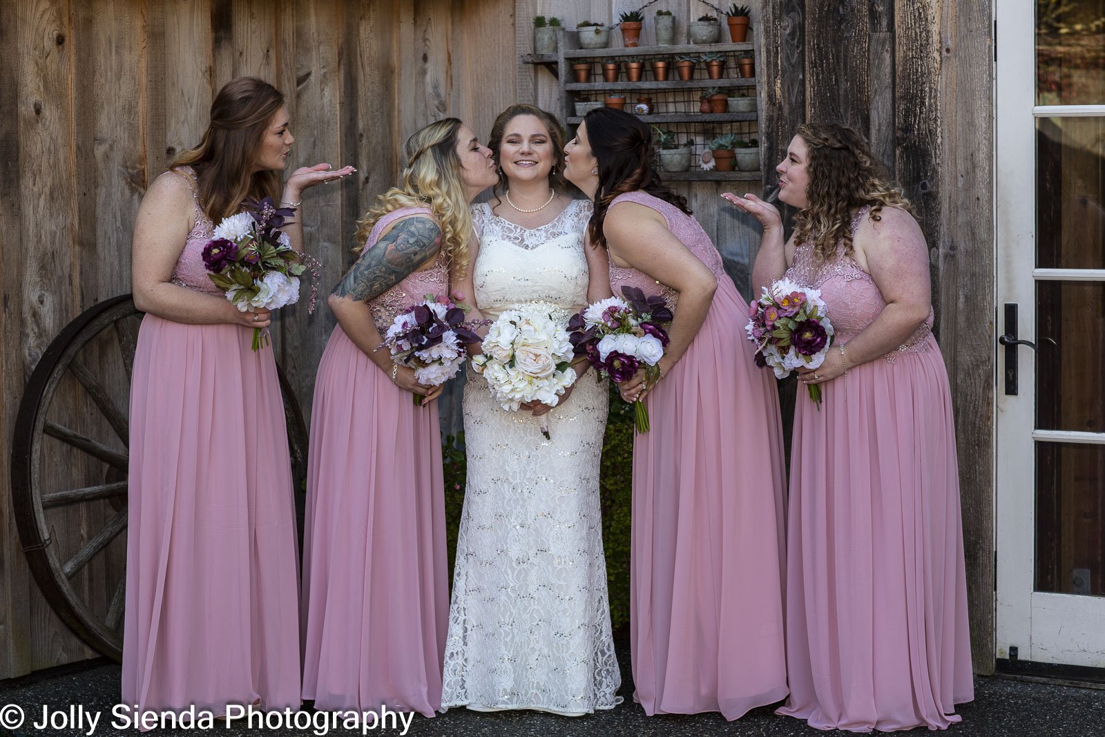 Bride and maids of honor kiss at Red Cedar Farm, wedding photogr