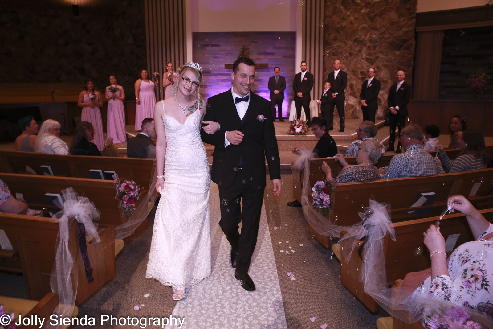 Husband and wife walks down the aisle in church wedding by Jolly