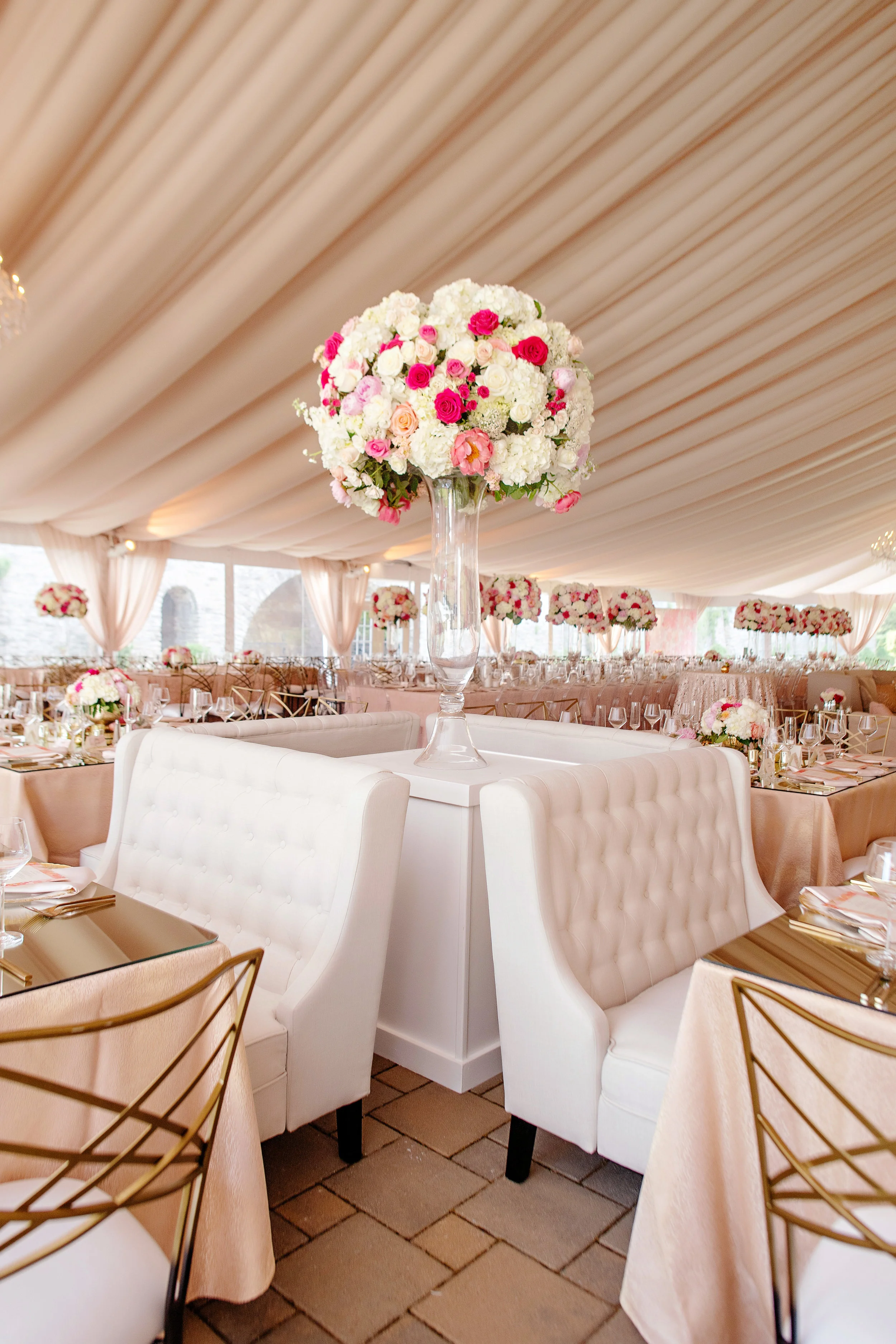 Outdoor tented reception with chandeliers and large focal arrangements in blush, magenta, and white by Yellow Canary Floral Design