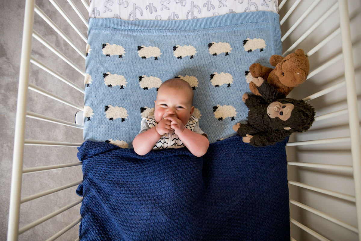 Happy baby ready for bed in cot Armstrong creek family and newborn photographer