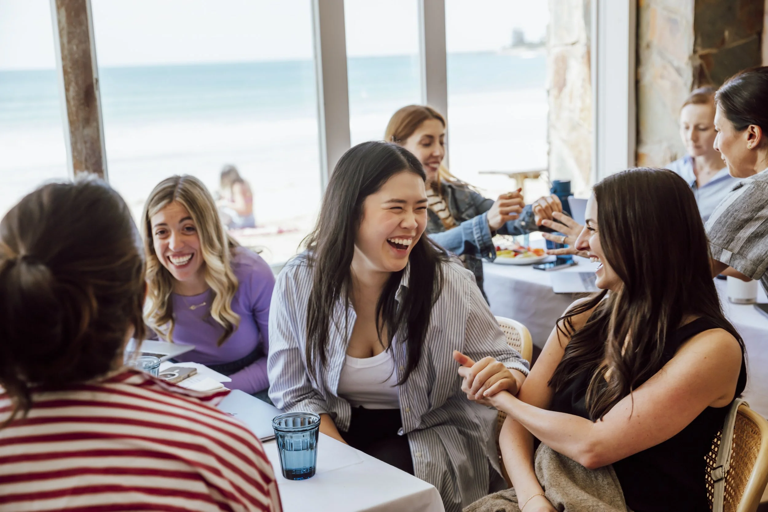 Team members laughing together at a beachside corporate offsite in Lorne