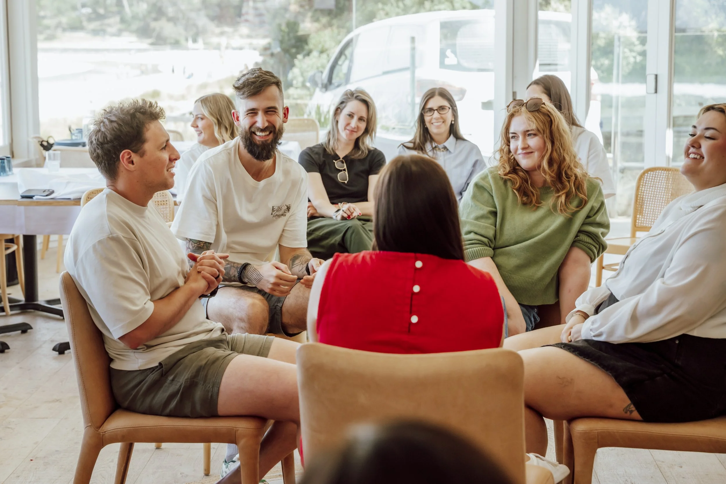 Colleagues sharing a laugh during a group discussion at a team building day in Lorne, Victoria