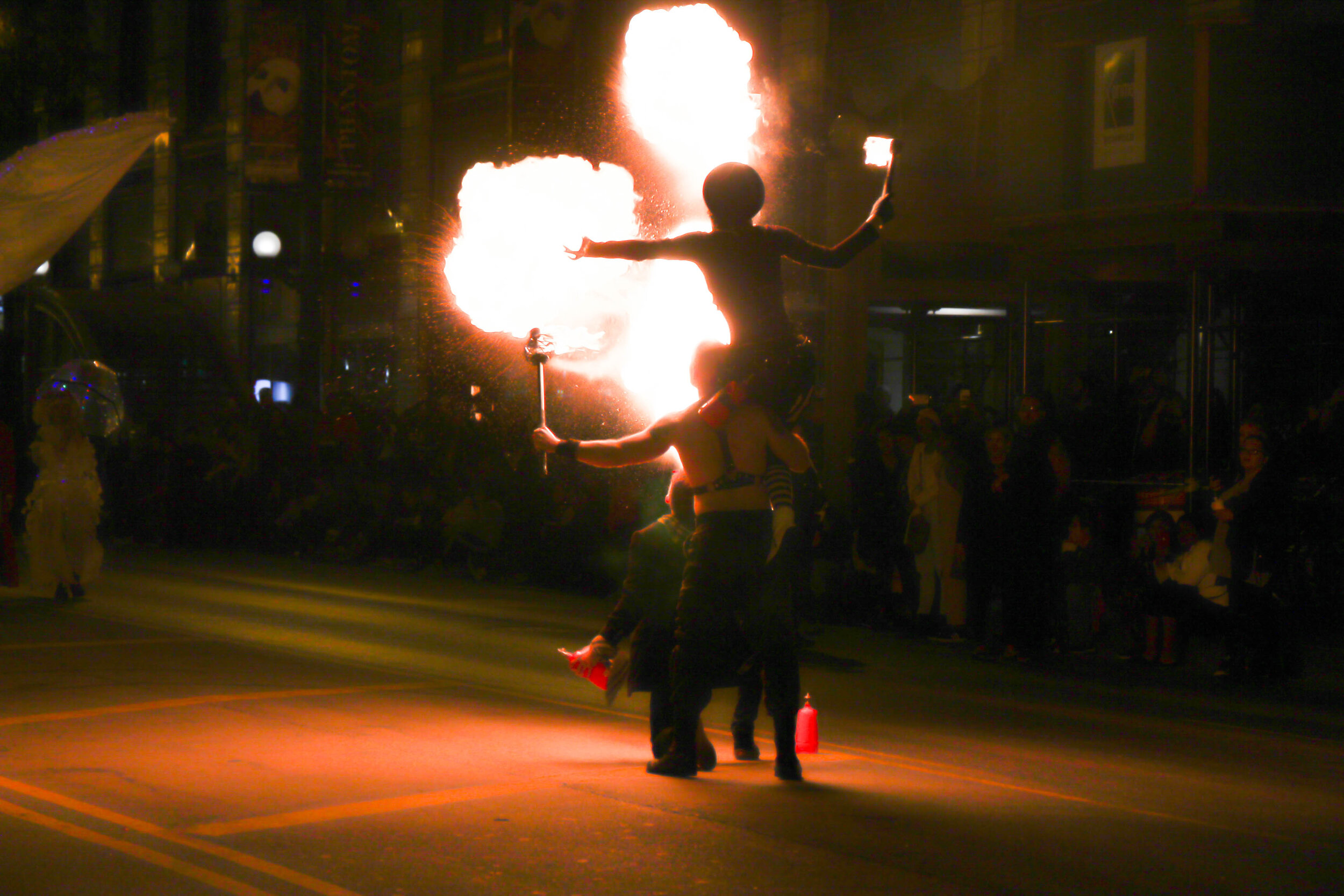 Two performers doing a fire-breathing demonstration at night during the parade.