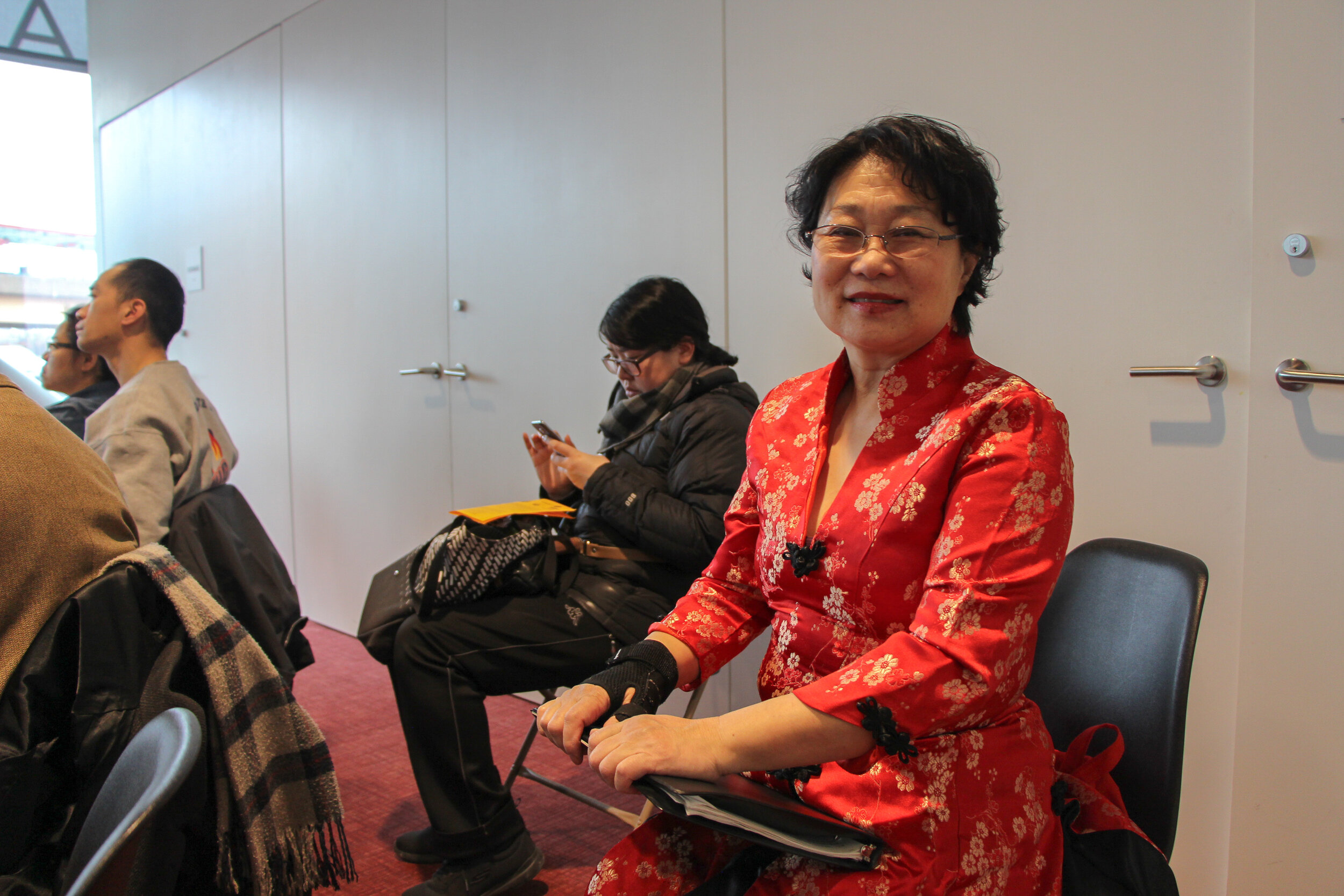  Member of the Dong Fang Performing Arts Chorus waits for her performance at the preparation area. The red printed-fabric pattern, named cheongsam, symbolizes luck, joy and vitality in Chinese culture. 