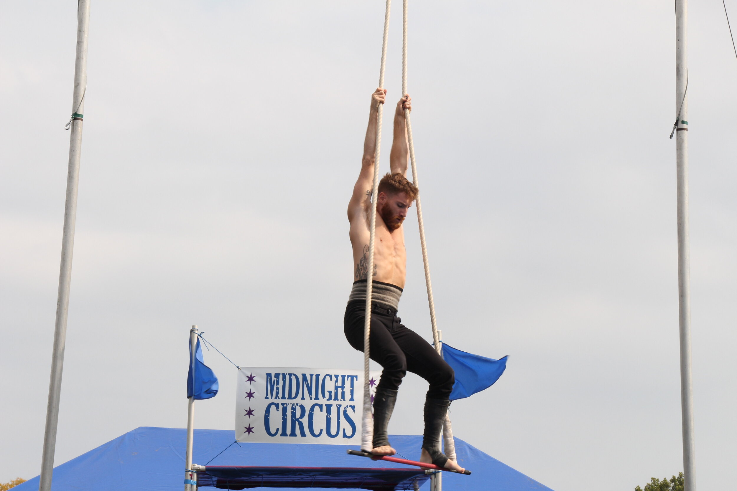  Kevin Beverley holds onto the ropes of the trapeze as he stands on the bar, preparing to perform his act.(Photo taken by Sabrina Hart) 