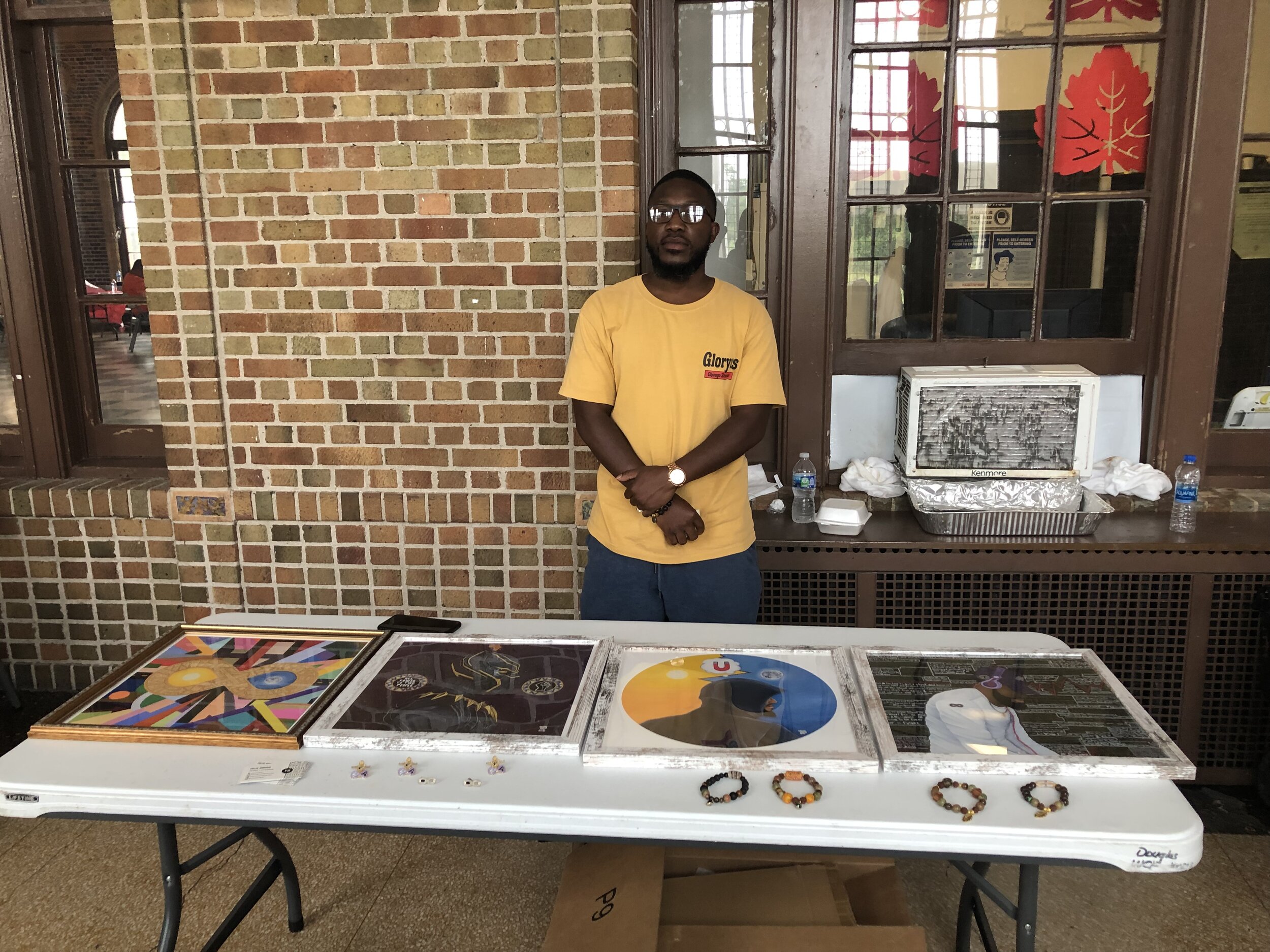 North Lawndale artist Felix Barnes selling artworks, bracelets, and enamel pins based on his art designs.