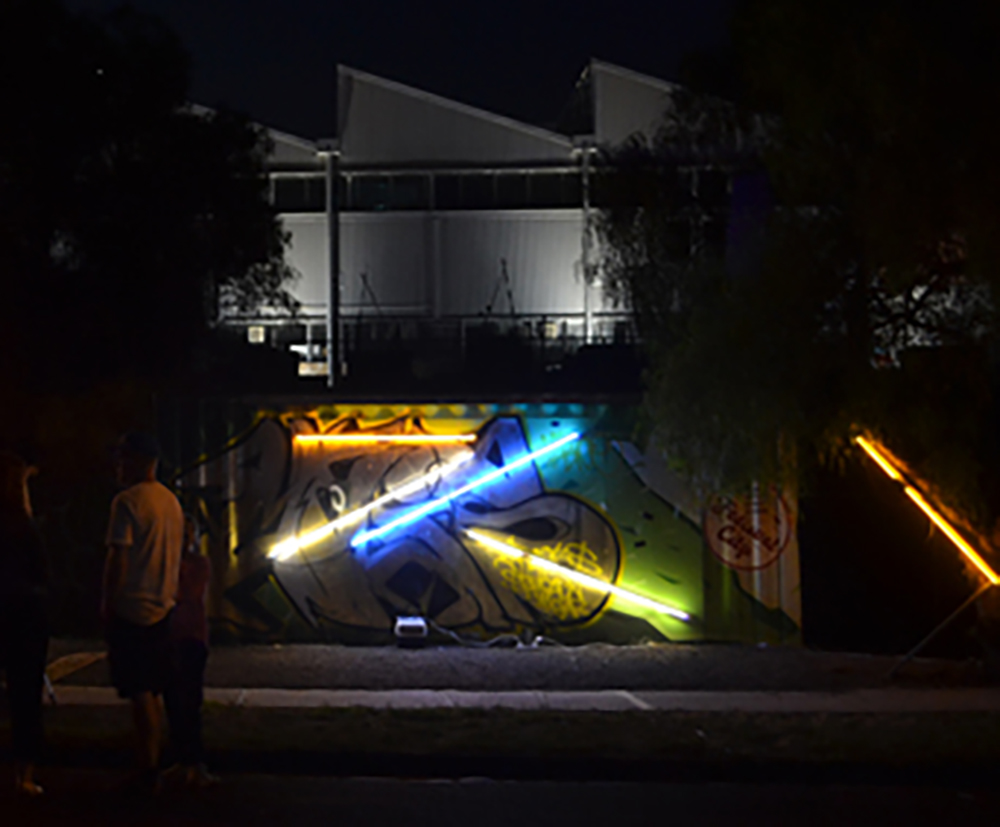 Contain Yourself - City of Maribyrnong Two containers on the banks of the Maribryong River were transformed into glowing, humming objects resonating with the low sounds of trains, birds and the river. The artwork combined light, sound and vibration. As the sun went down, the colours became more vivid and the sounds spread like a dream . Neon by Fiona Hillary .