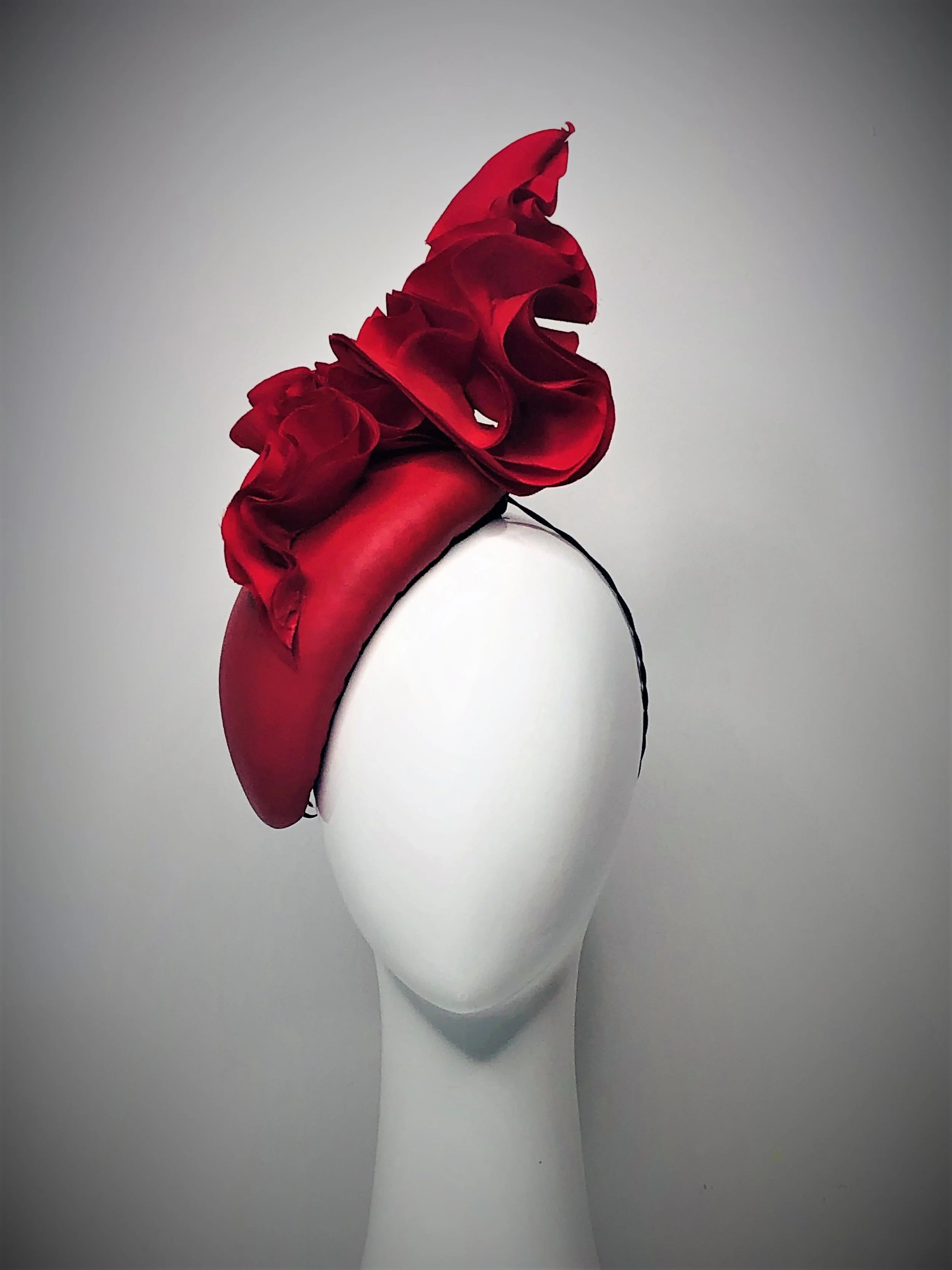 Rich red leather, side of the face hugging  race hat with ripples of red silk waves .