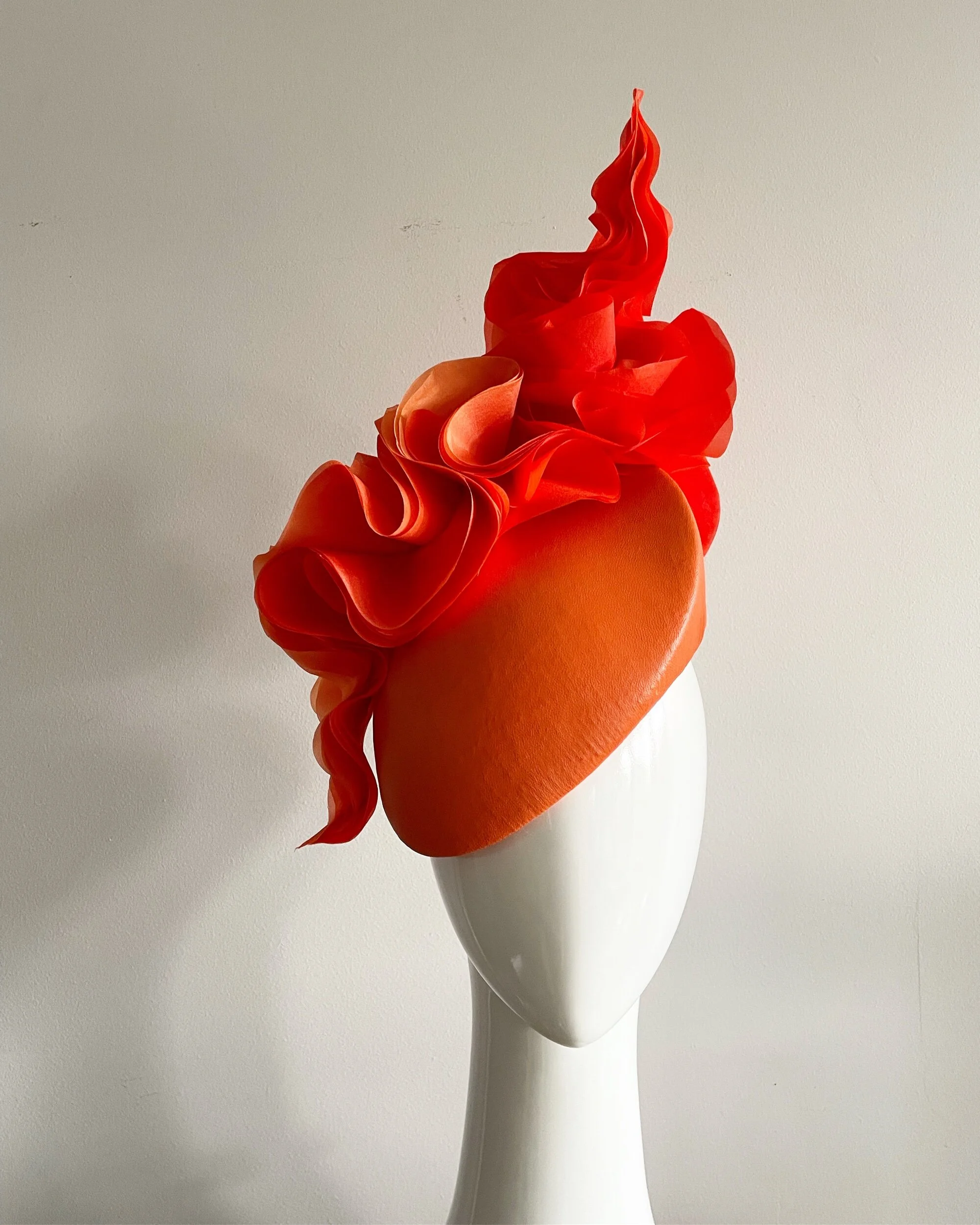Standout orange leather hat with fluid waves of silk