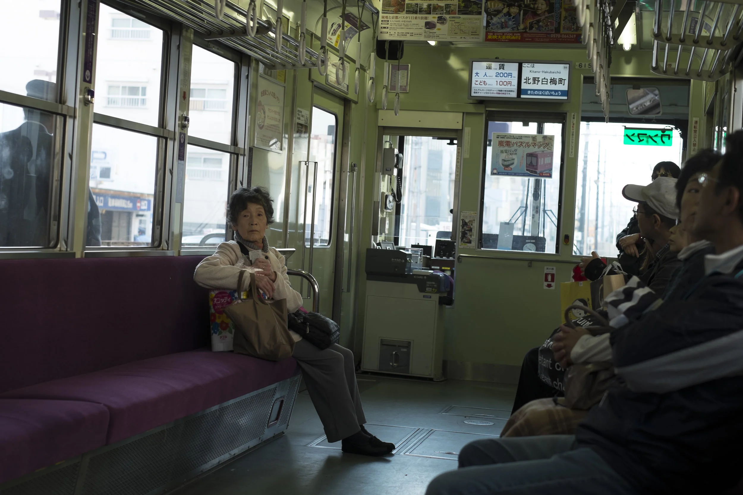 An old lady sits opposite to all people in the train, Kyoto, Japan