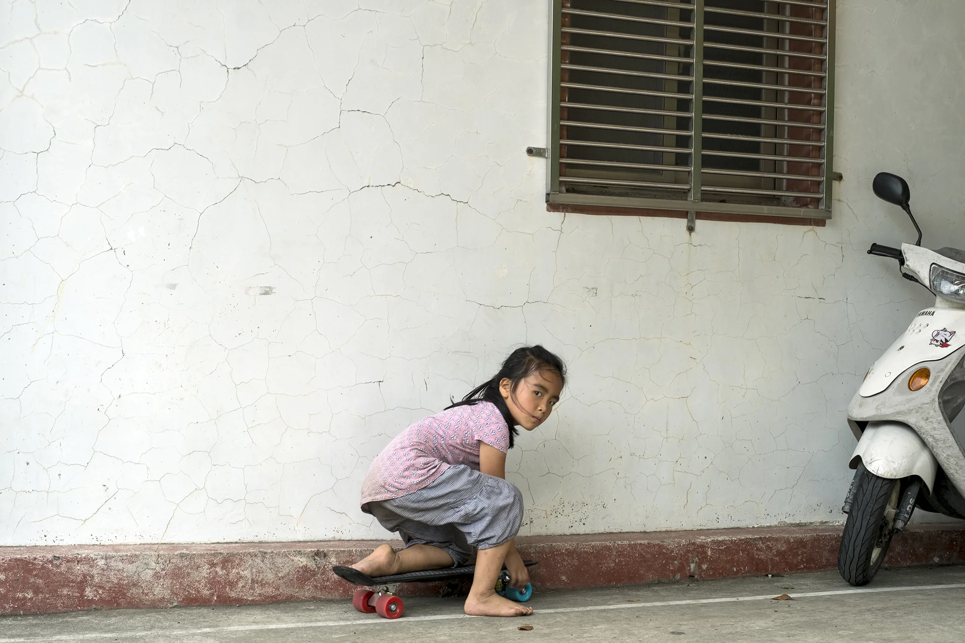 An aboriginal little girl Saji Yahan stares at me on her skateboard, Piyaway, Taoyuan, Taiwan