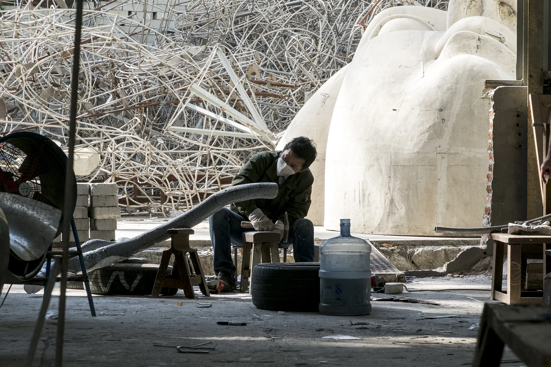 A worker works for a new sculpture in front of hundreds of abandoned skeleton models, Xiamen, China