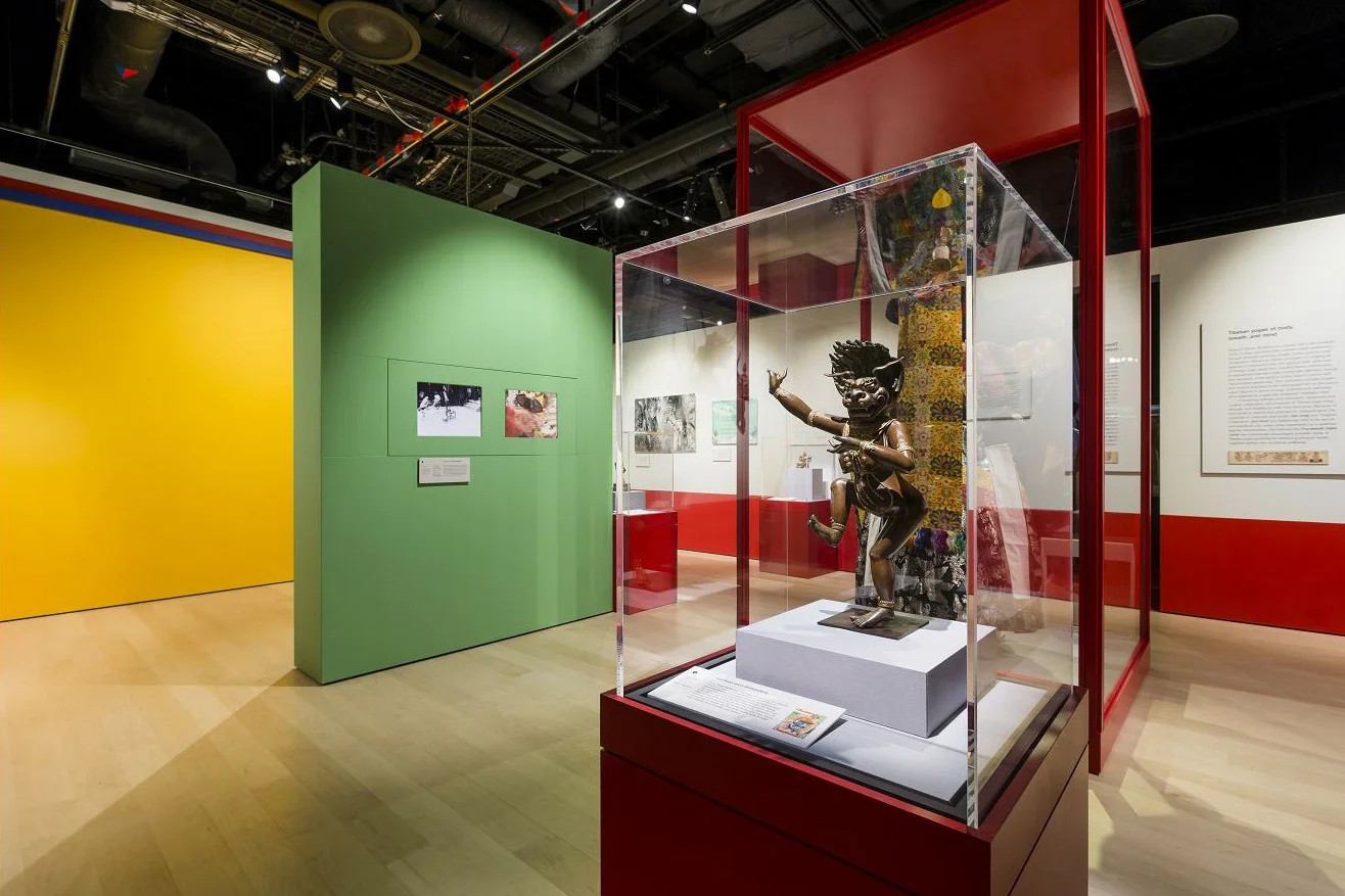 An installation shot from an exhibition. In the foreground is a display case with a sculpture.