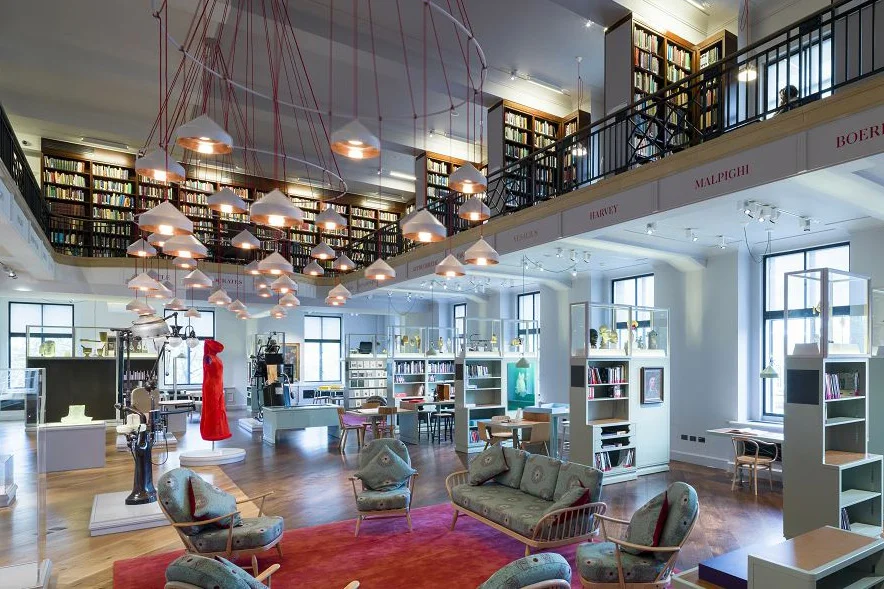A bright, airy reading room in a library. with seats, bookshelves, and suspended lights.