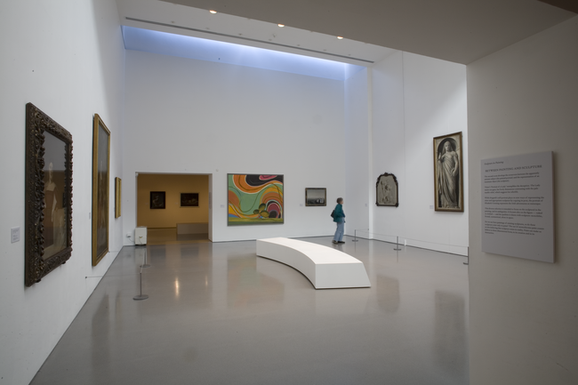 Exhibition of paintings in a large, white gallery space.