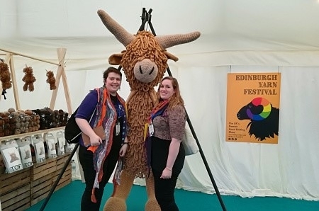 Tipsy Knits podcasters Cia and Pip and Edinburgh Yarn festival next to a large crafted Highland Cow