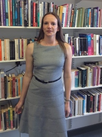 [Image Description: Professor Hammill stands in front of a bookshelf completely full of books