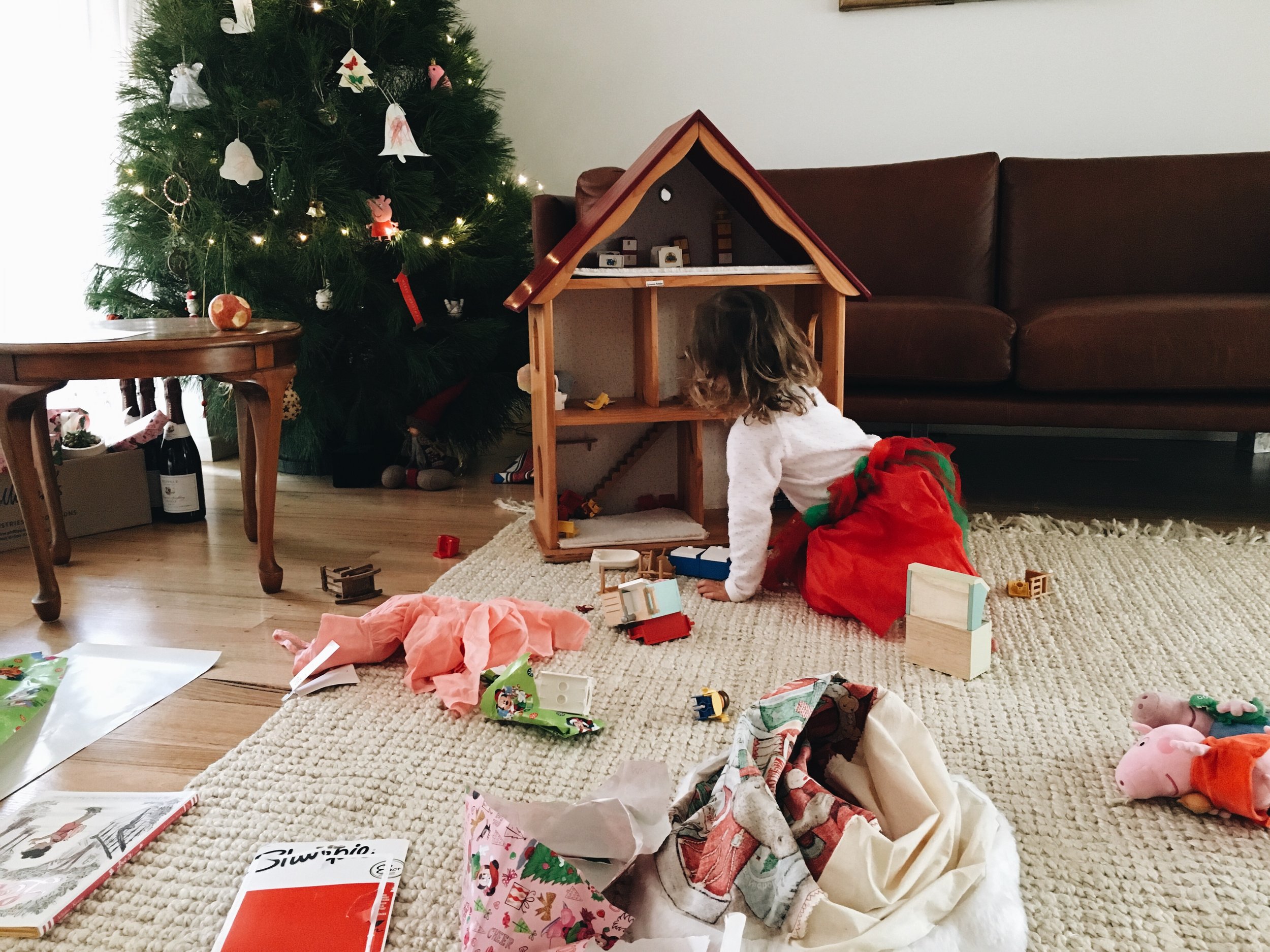 Wearing a tutu and playing with her new doll's house.