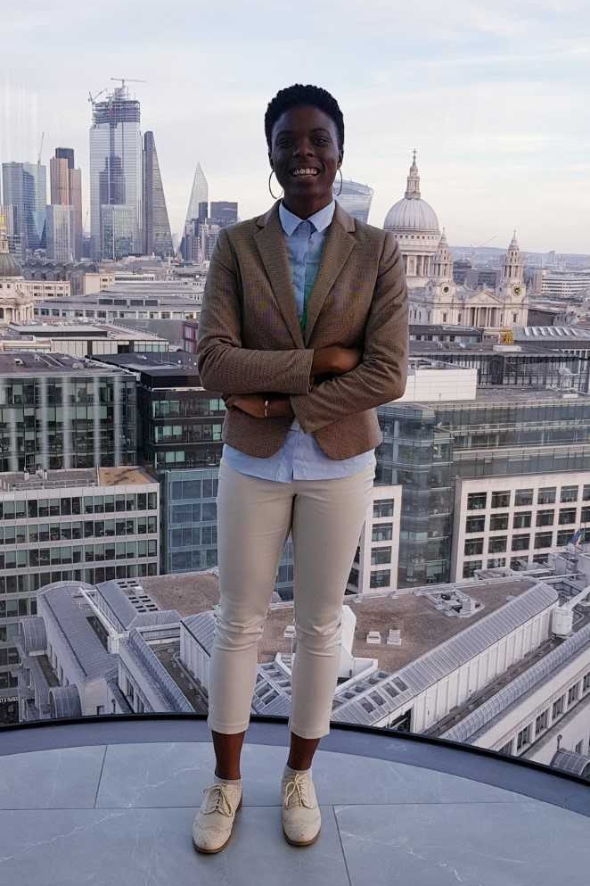 Nia in front of a skyline view of Central London from the Deloitte building for the Business Plan Competition Pitch Day