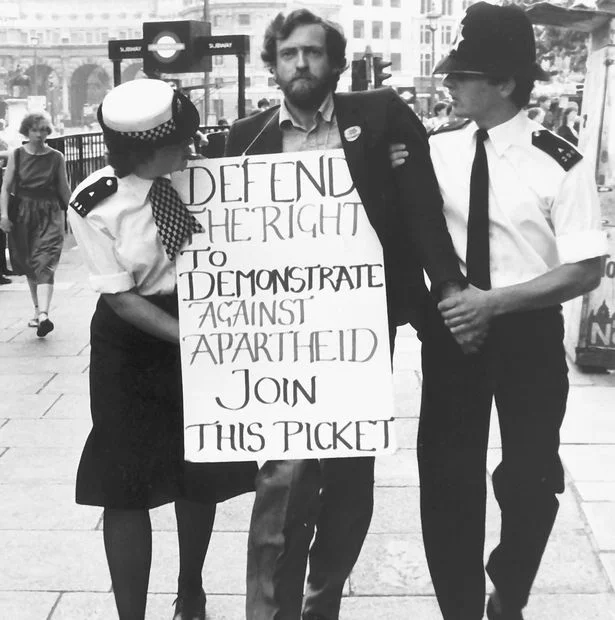 Here's Jeremy Corbyn getting arrested outside South Africa House in 1984. The photo was taken by Rob Scott ; read more about it here .