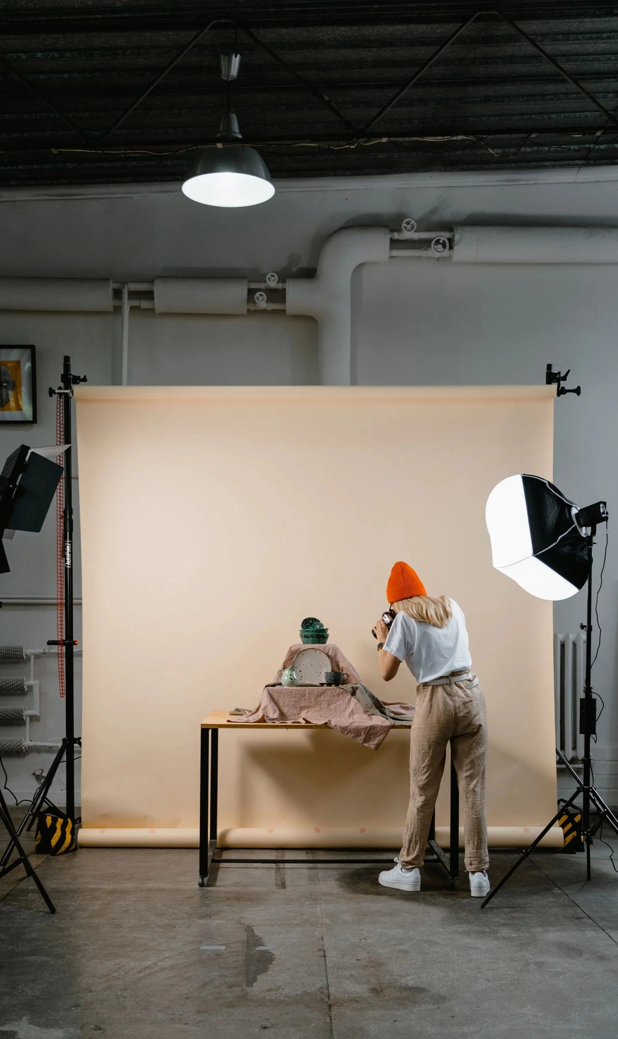 A photographer arranging and photographing products in a professional studio surrounded by lighting equipment.