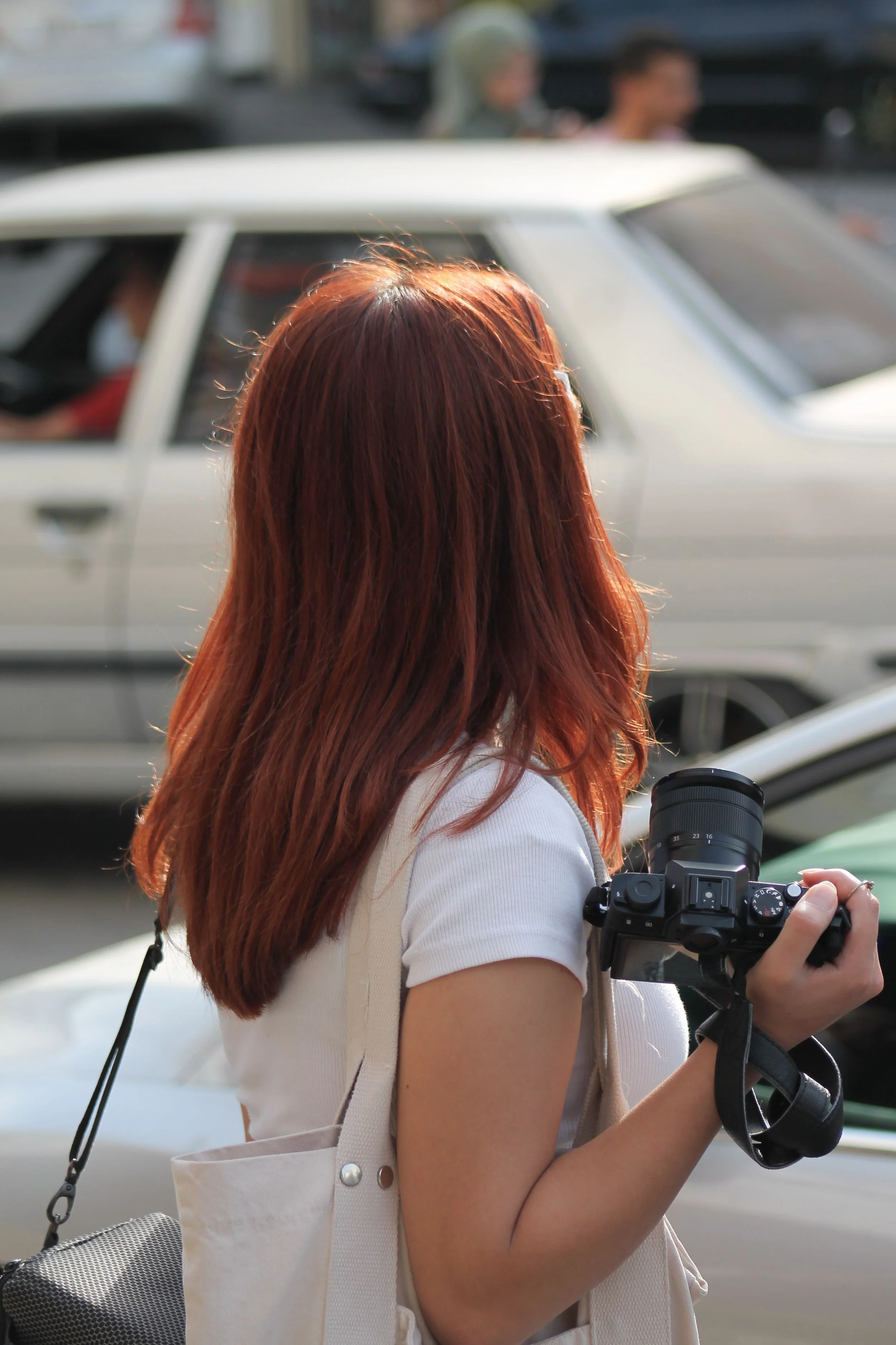 Photographer carrying a camera beside parked vehicles before a client shoot, illustrating business mileage tracking and bookkeeping for photographers.