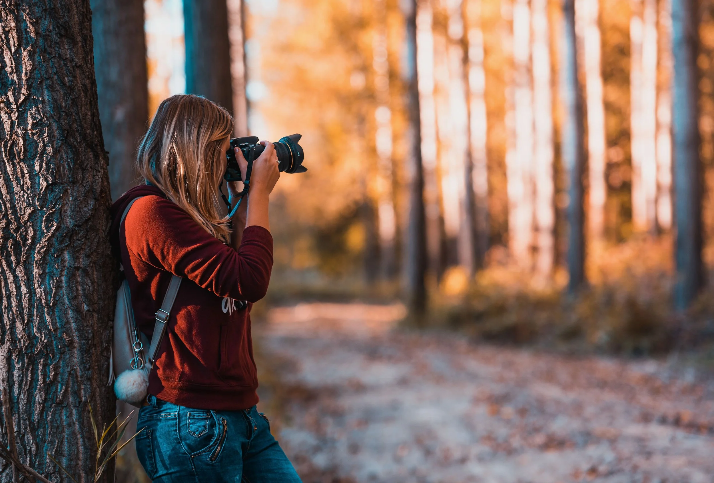 A professional photographer takes photos on location in a wooded area.