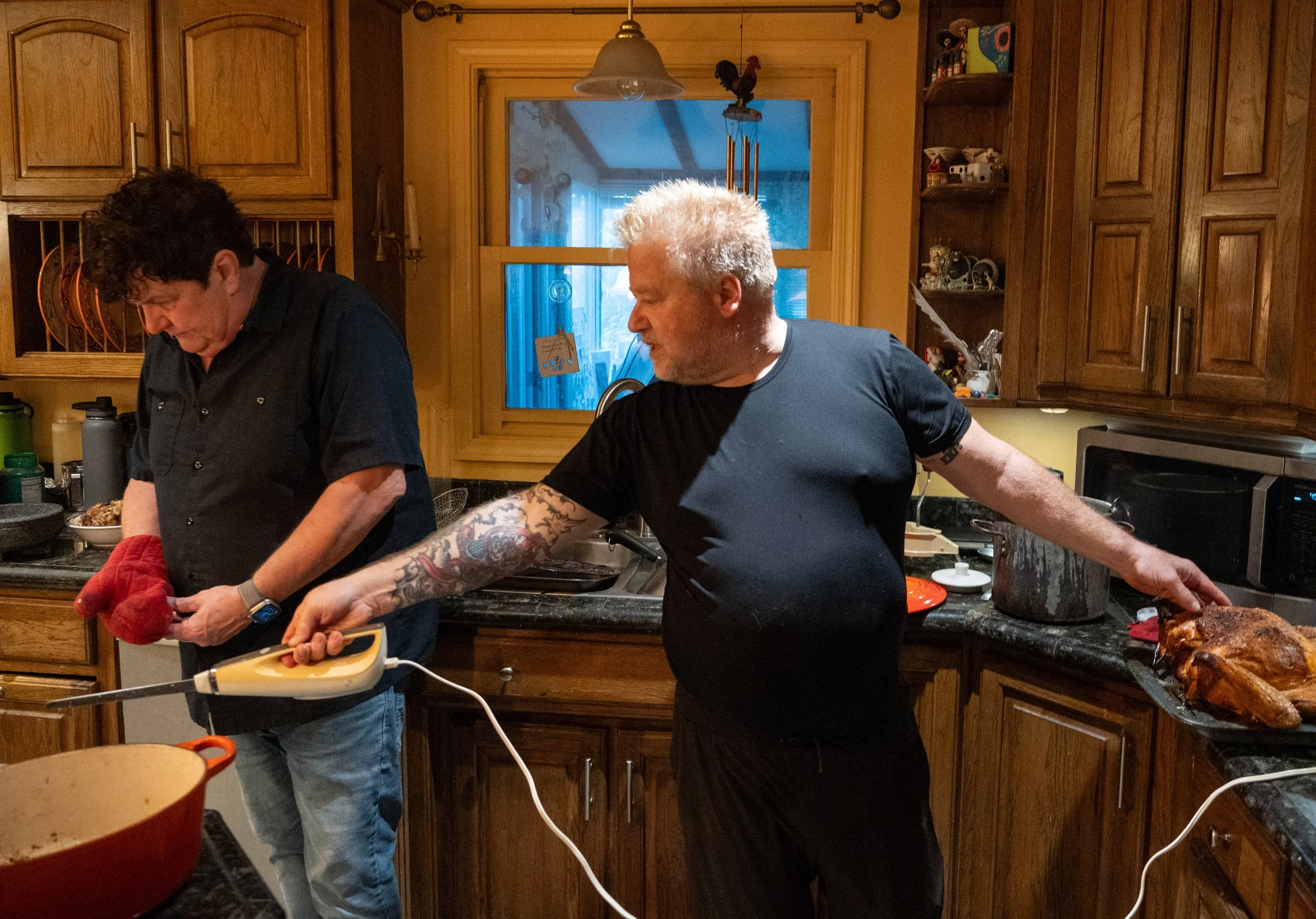  J.J.Pearson pauses his turkey carving to instruct David “Tufty” Clough in his kitchen Thursday, Nov. 23, 2023. 