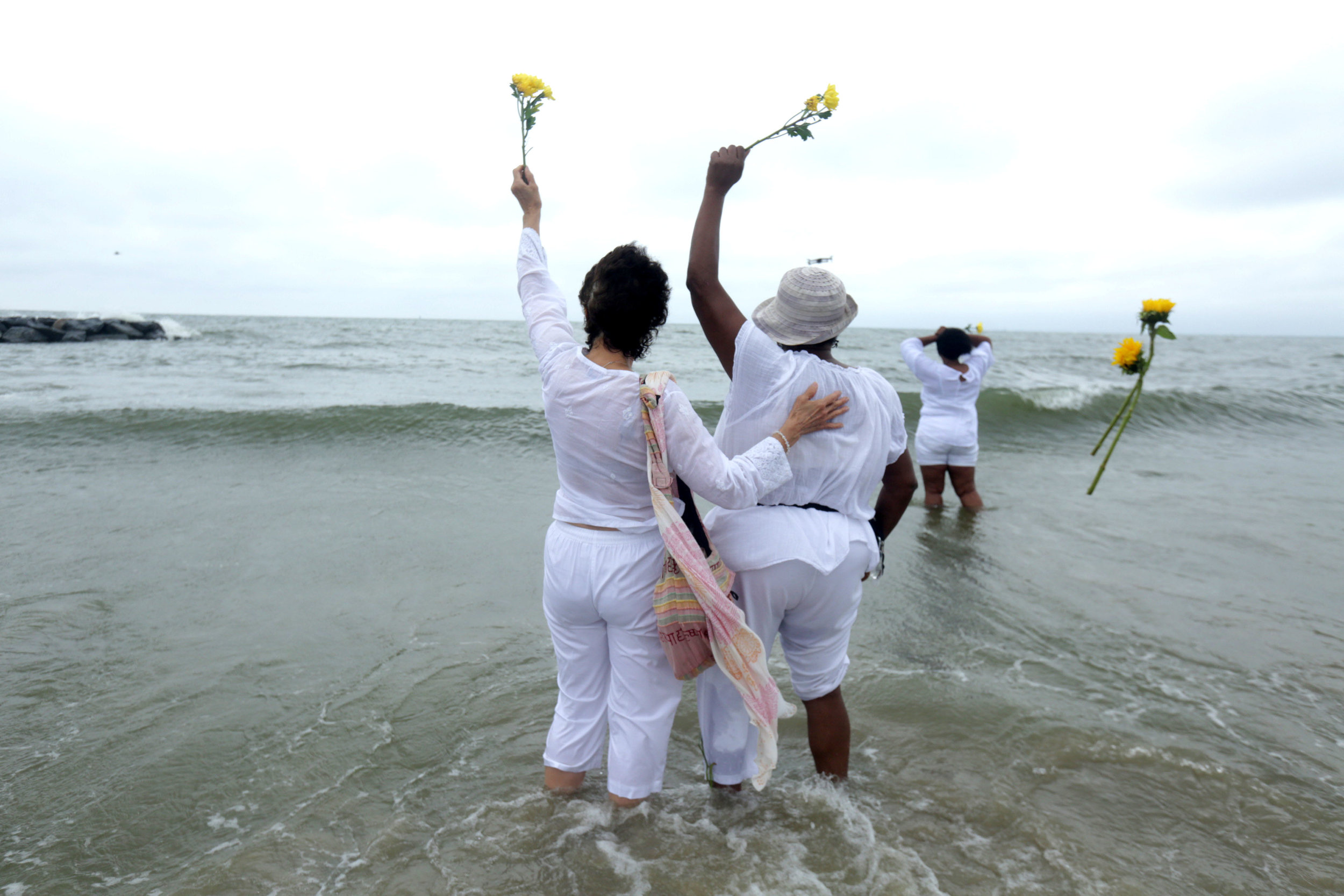  Nancy Alvarado and Beulah Macelin stand together as they throw their flowers into the ocean during the Day of Remembrance ceremony on Saturday. 