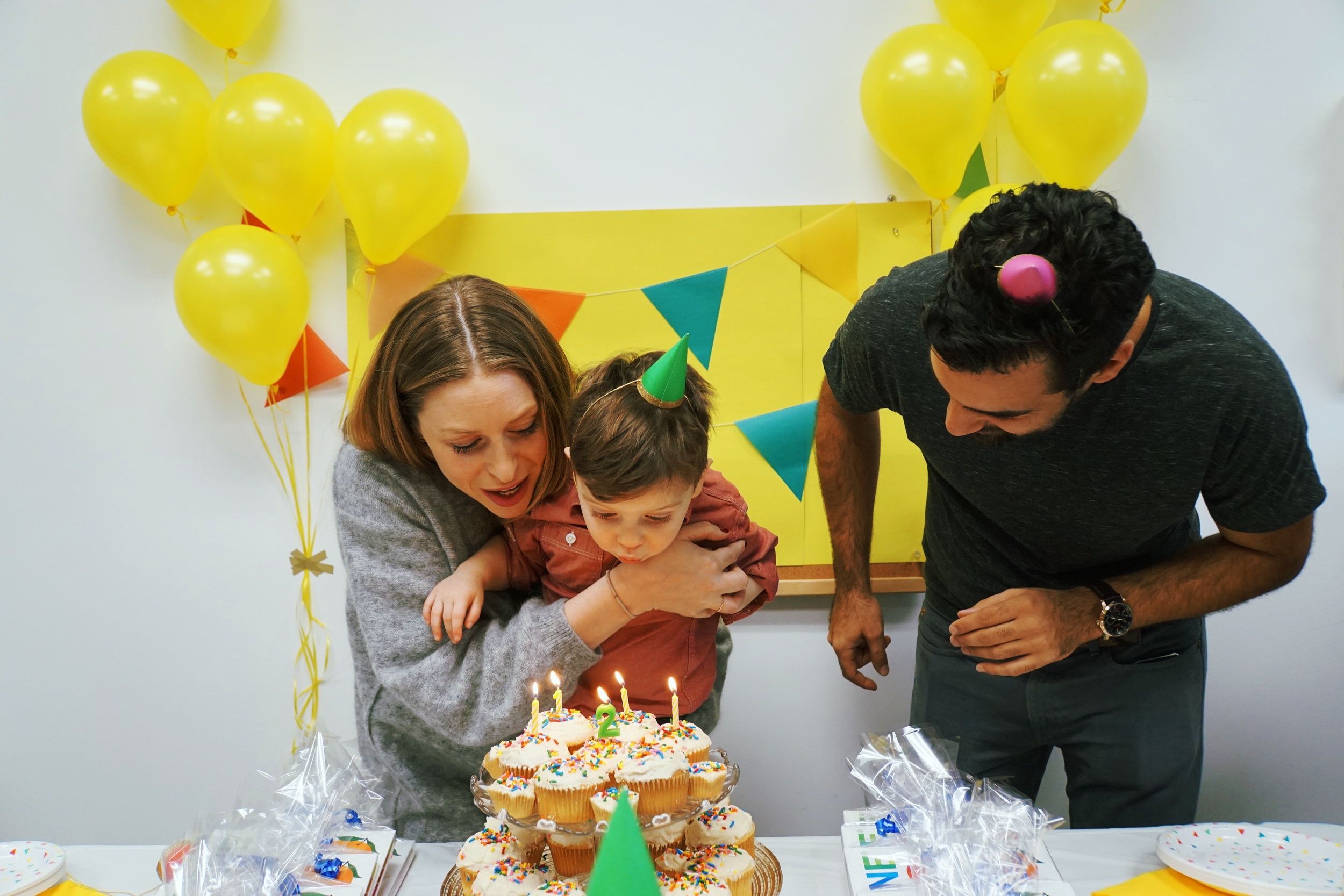 Parents with child blowing out birthday candles.  (Copy)