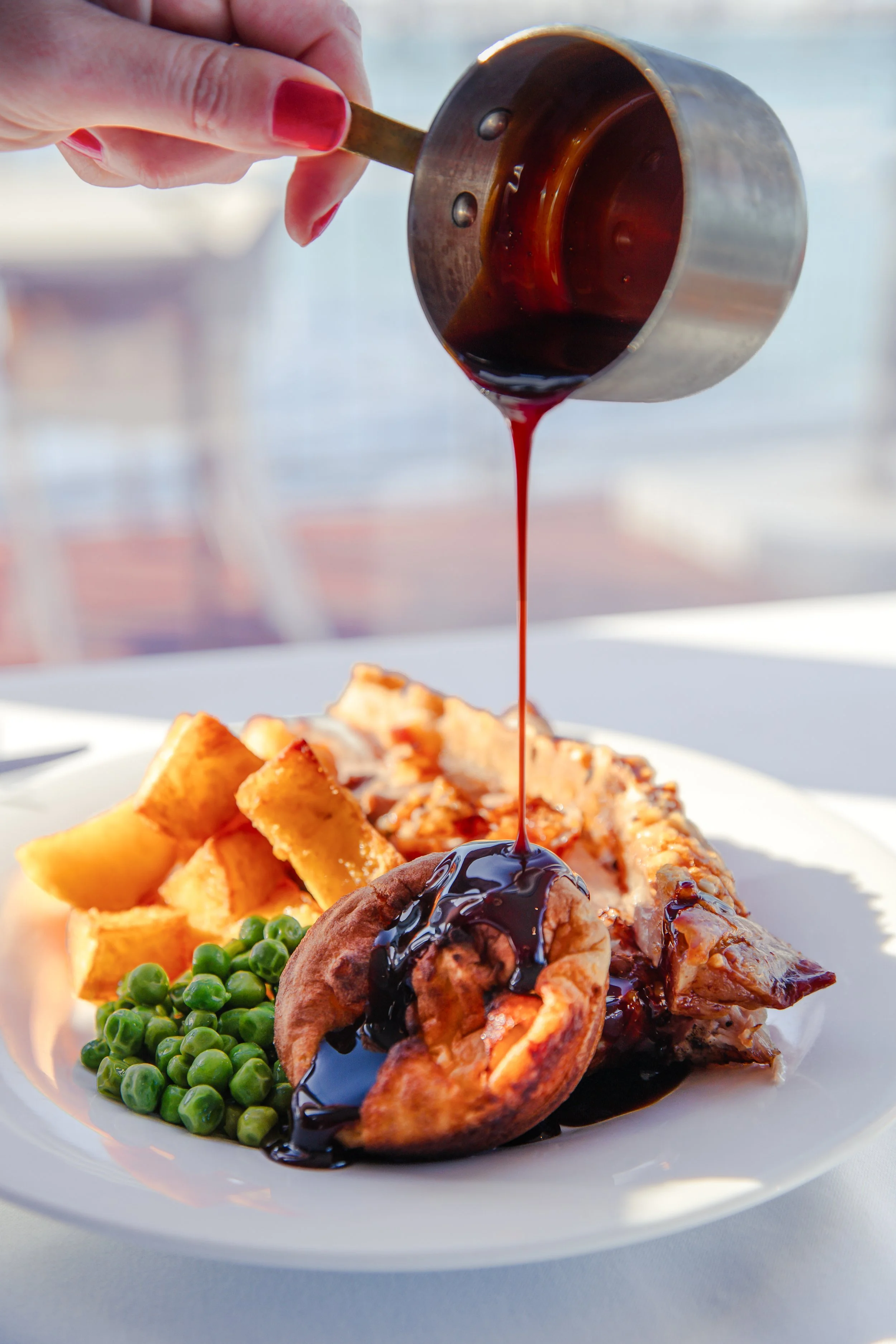 a sunday roast pork, served with green peas, roasted potatos, Yorkshire pudding, rich gravy and harbour views.