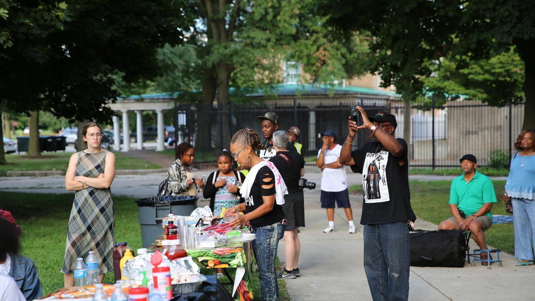 Event attendees and community members look on as the poets perform, and partake in the picnic refreshments provided.